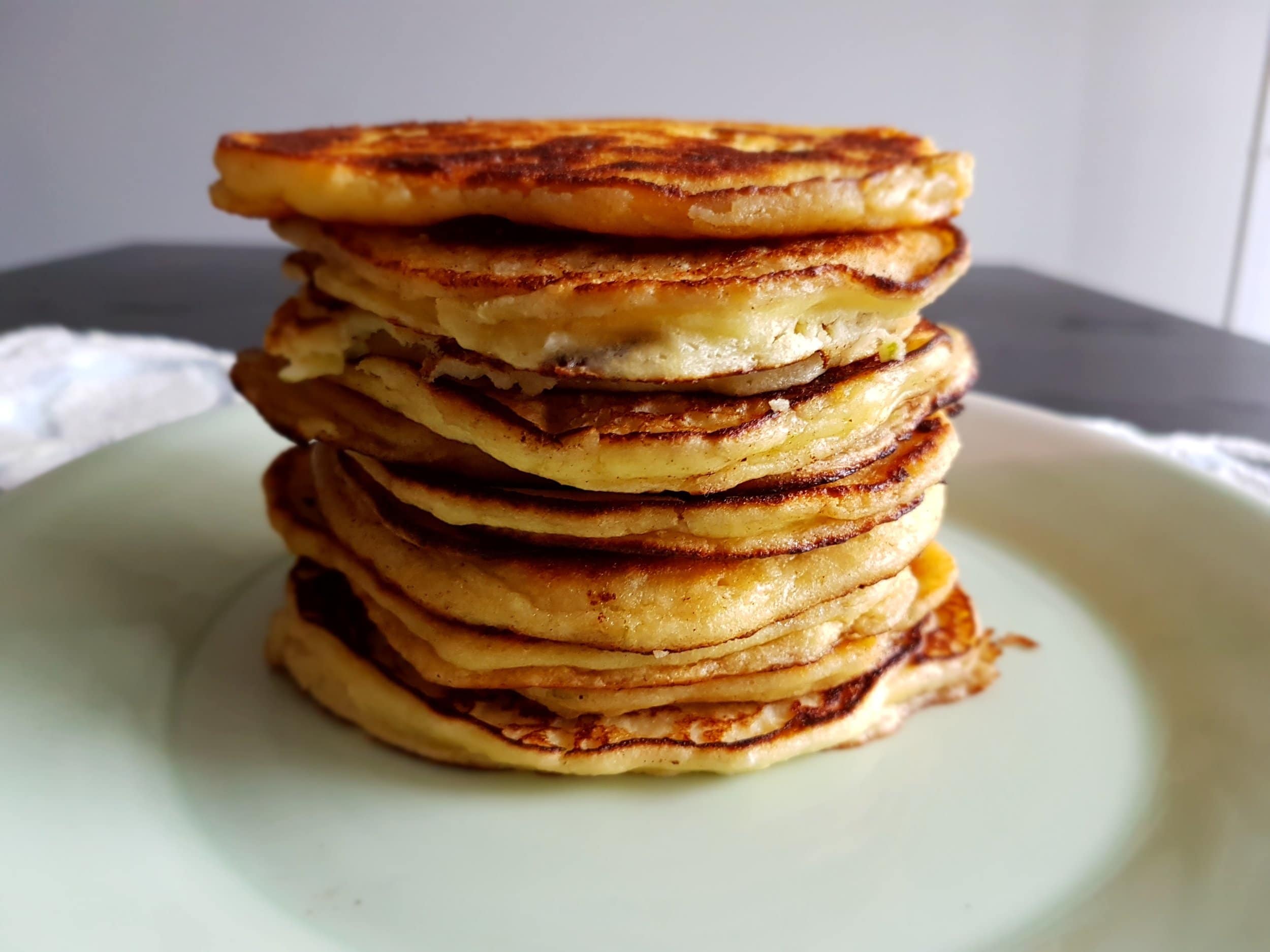 Fluffy Coconut Lime Ricotta Pancakes piled high on the plate.