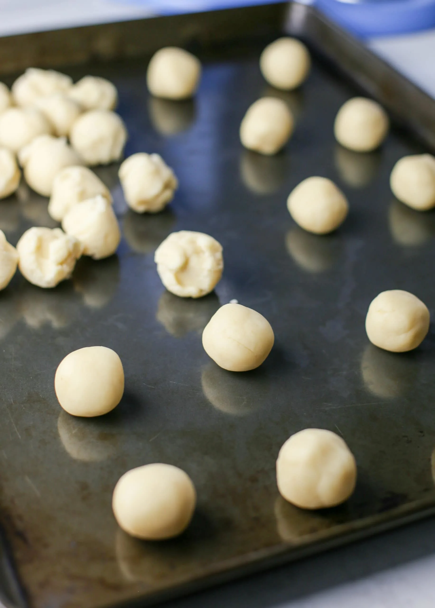 Raw condensed milk cookie dough balls on a baking sheet.