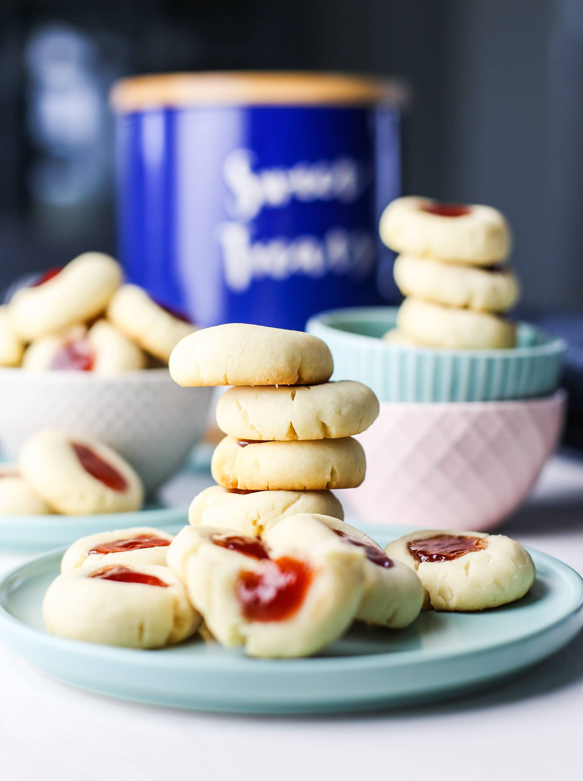 Condensed milk thumbprint cookies piled in two bowls and on a plate.