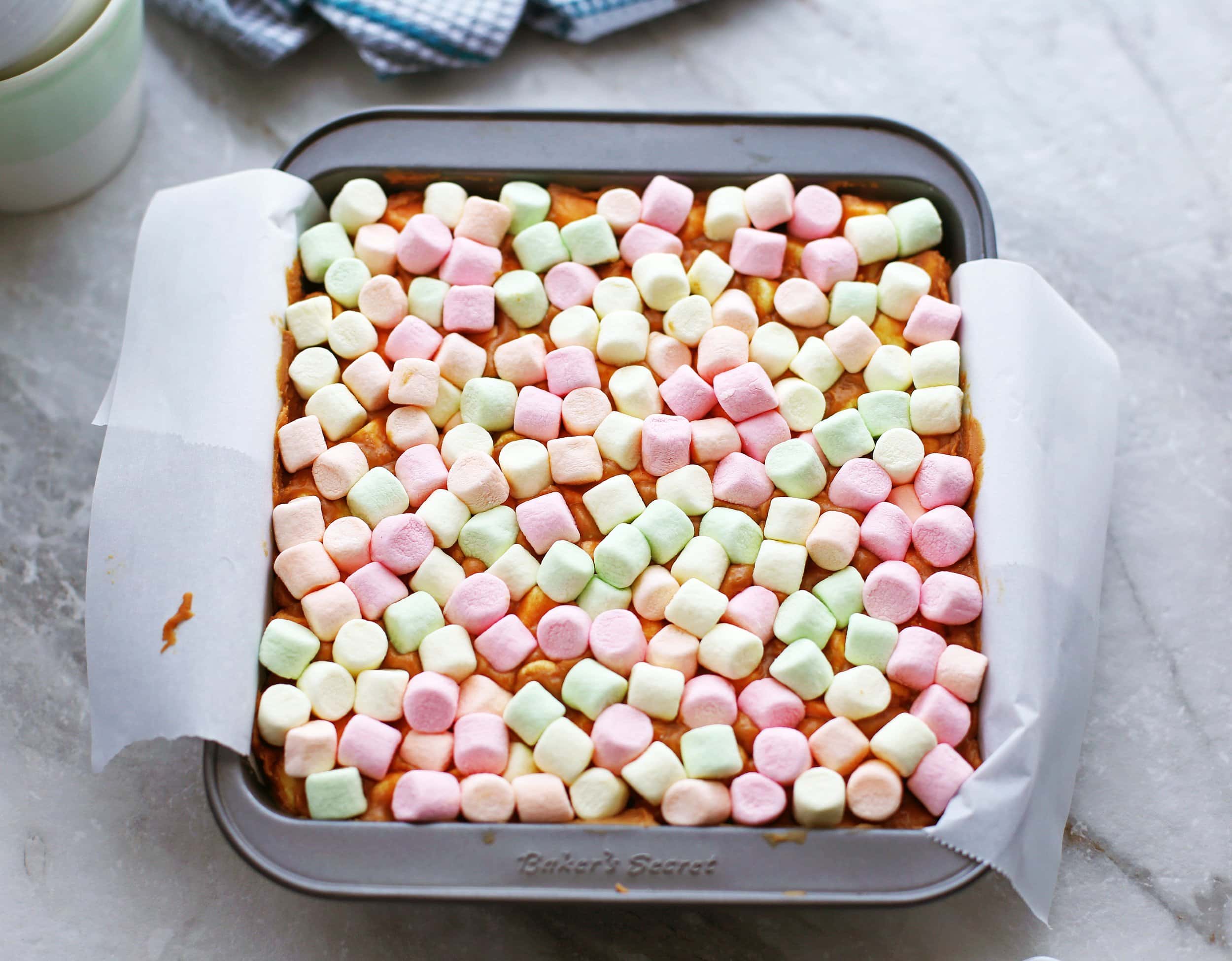 Combined confetti bar ingredients in a square parchment paper lined baking dish.