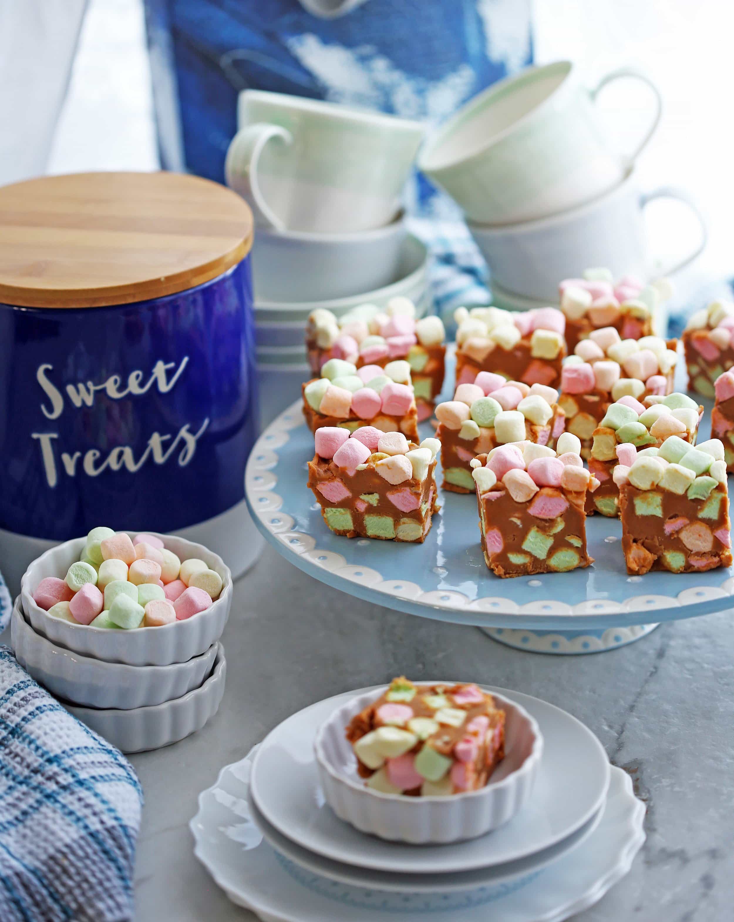 Side angled view of peanut butter butterscotch marshmallow bars (aka confetti bars) on a cake stand.