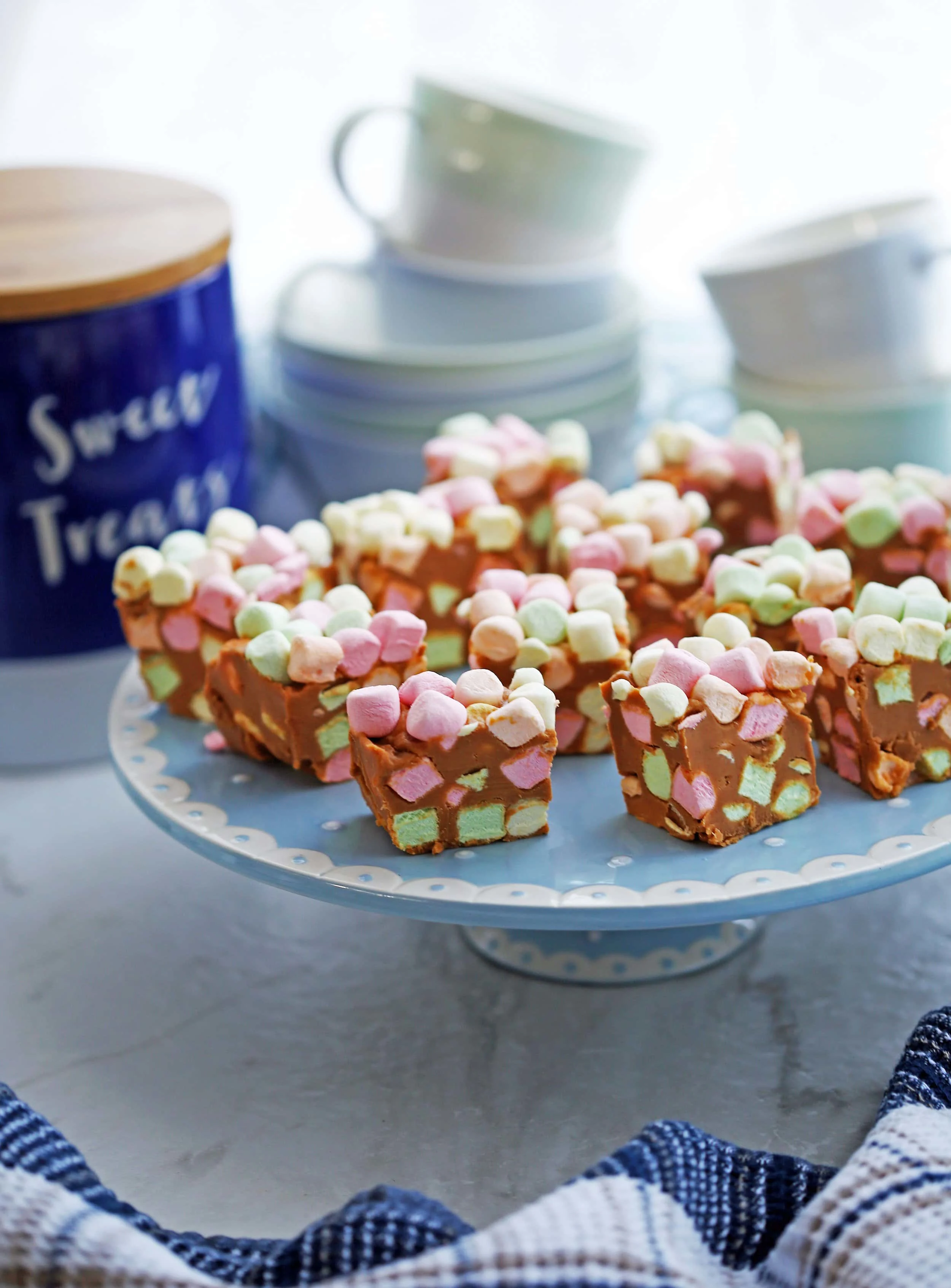 Side view of peanut butter butterscotch marshmallow bars (aka confetti bars) on a cake stand.