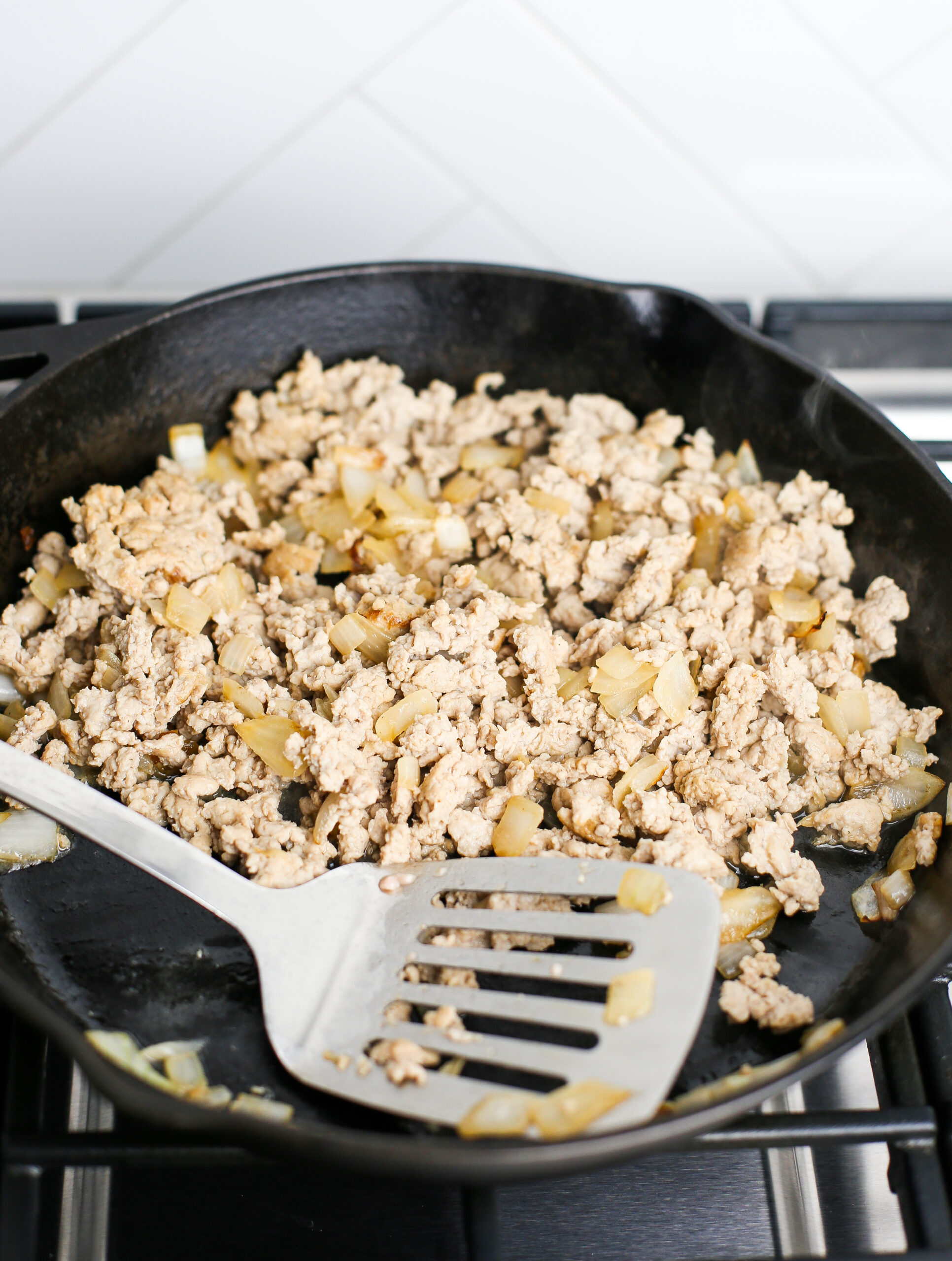 Cooked ground chicken and onions in a cast iron skillet.