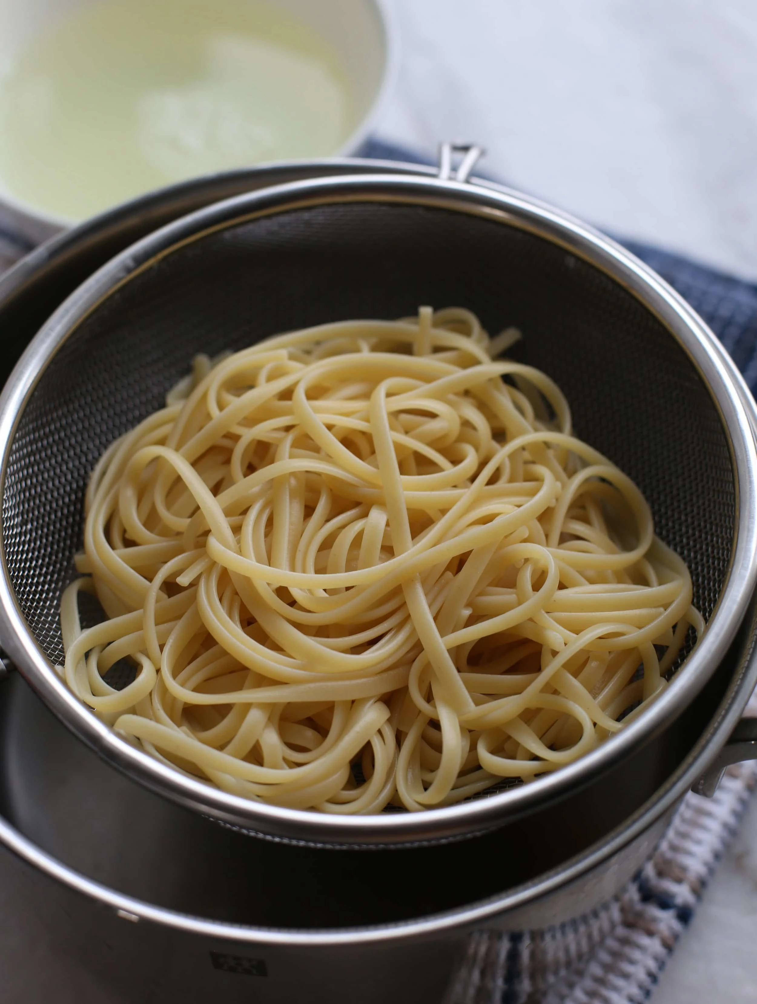 Cooked pasta placed in a metal stainer.