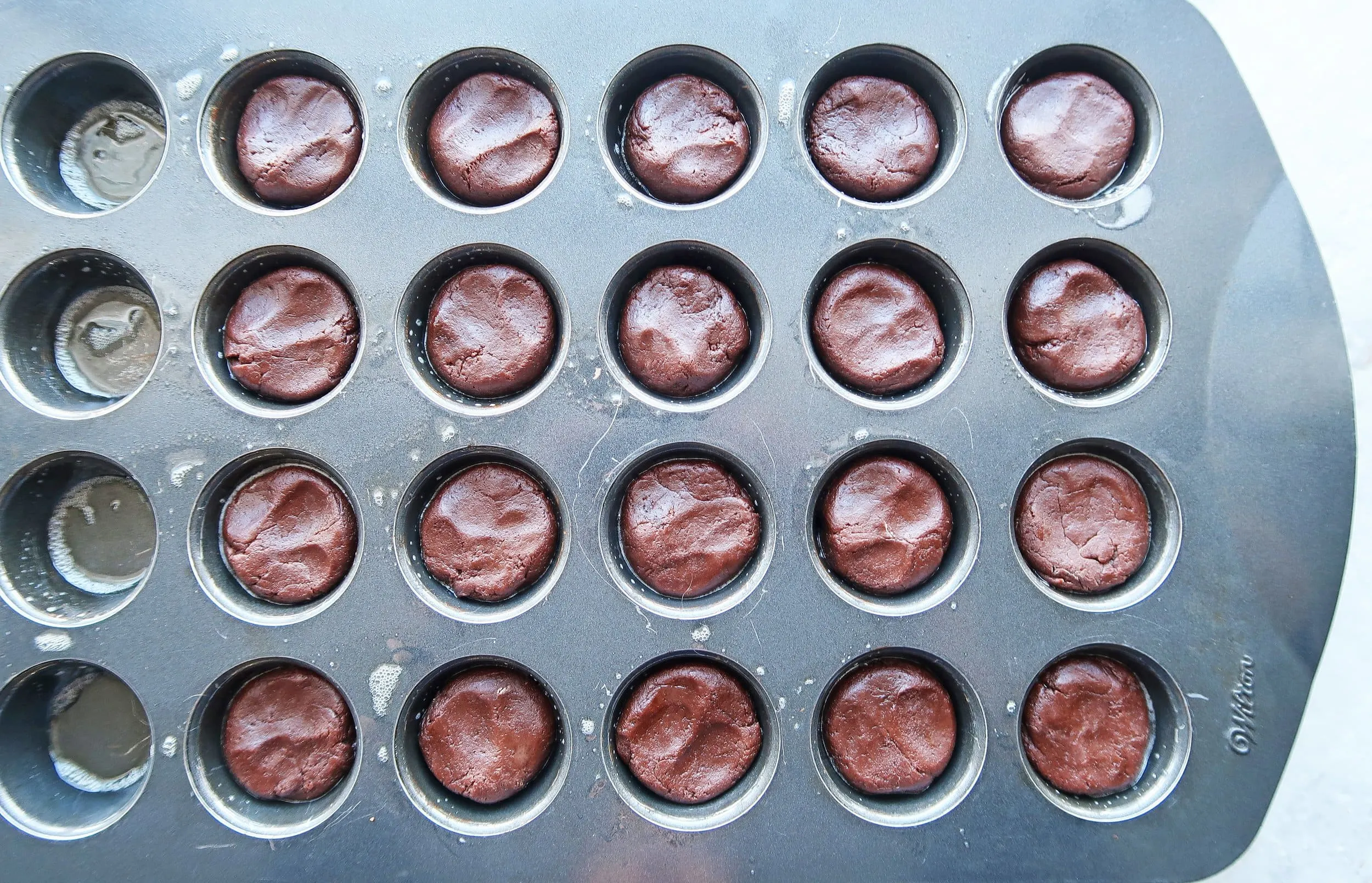 Cookie dough pressed into a muffin pan.