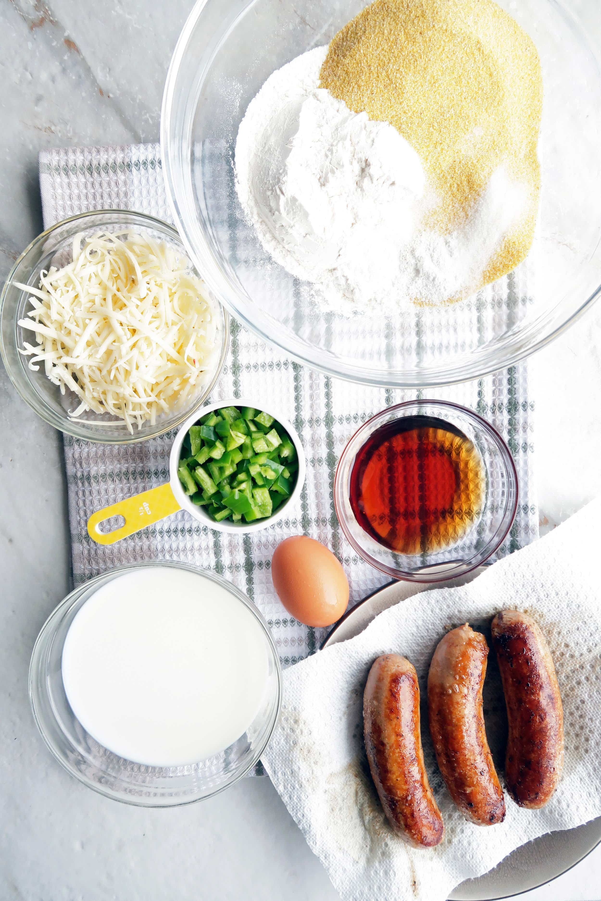 Cornbread ingredients including corn meal, flour, sausage, maple syrup, jalapeño, milk, and cheese.