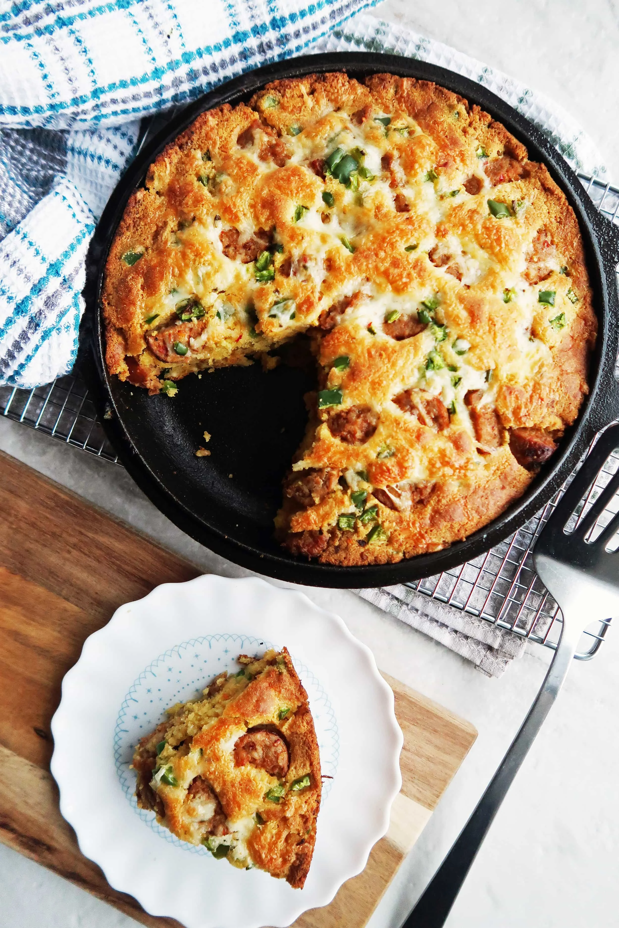 Jalapeño maple and sausage cornbread in the skillet with a slice on a white plate.