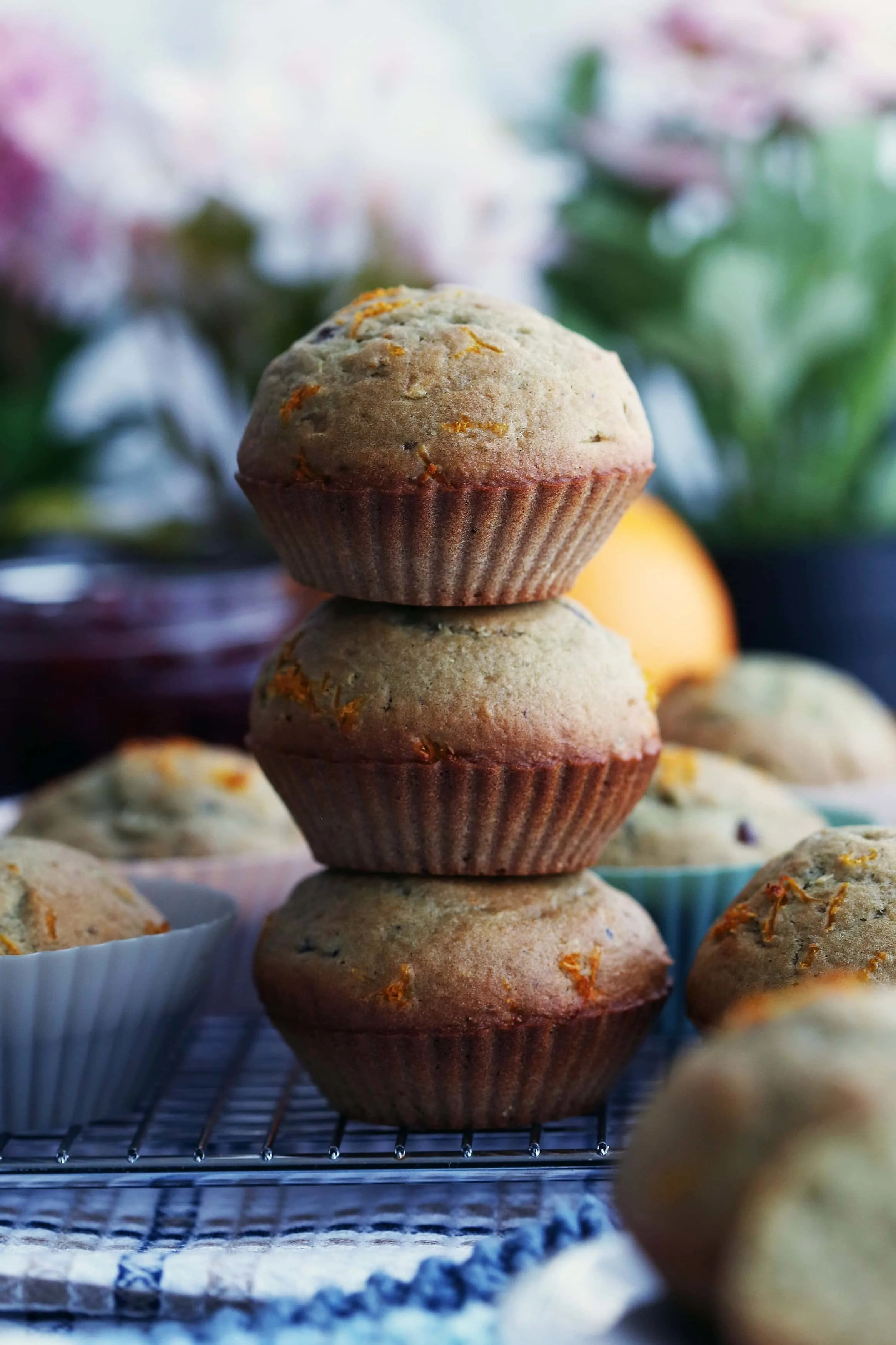 A closeup side view of three cranberry orange muffins on top of one another.