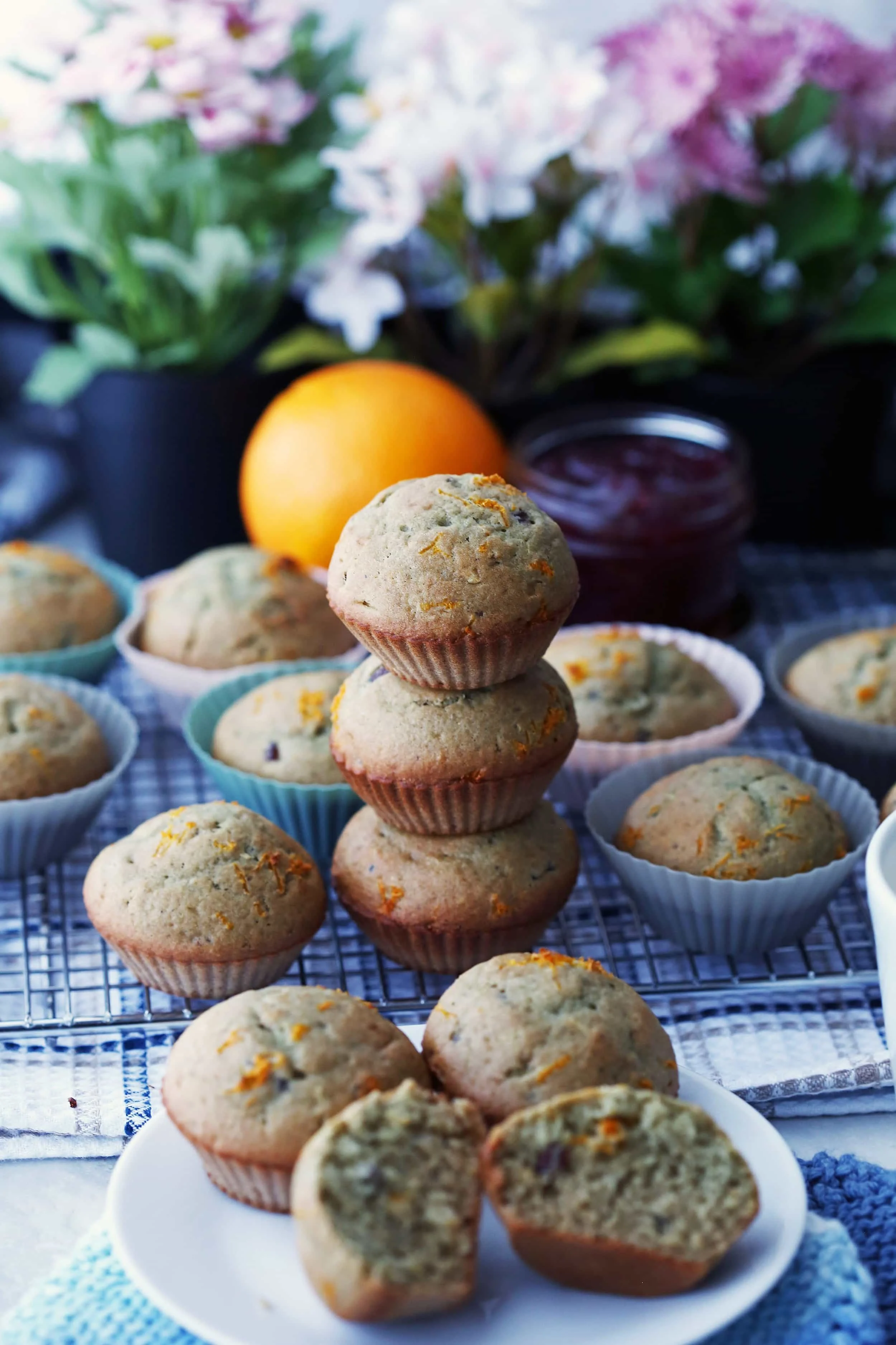 Many cranberry orange muffins on metal cooling rack and on a white plate.