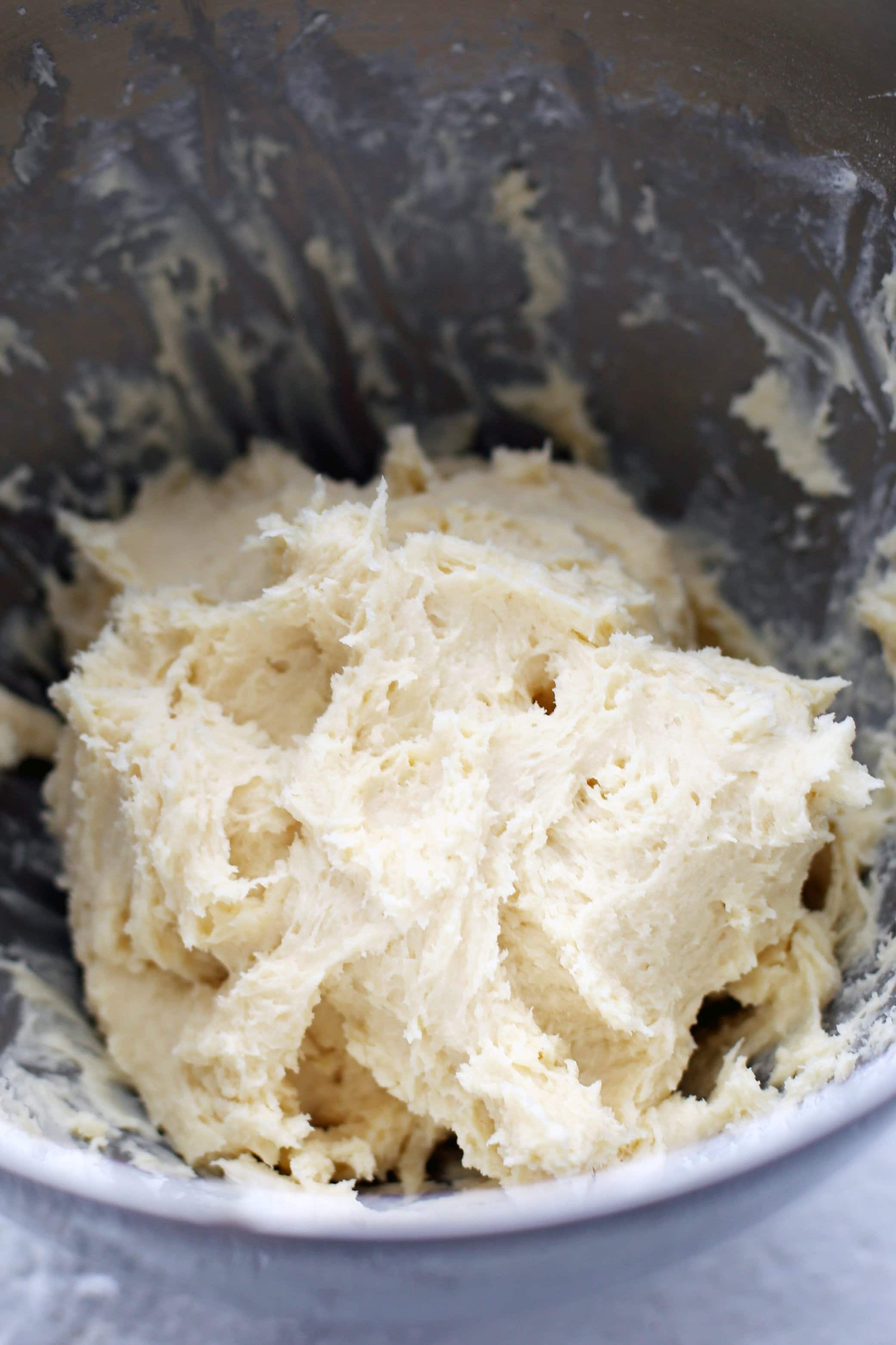Cream cheese cookie dough in a large metal mixing bowl.
