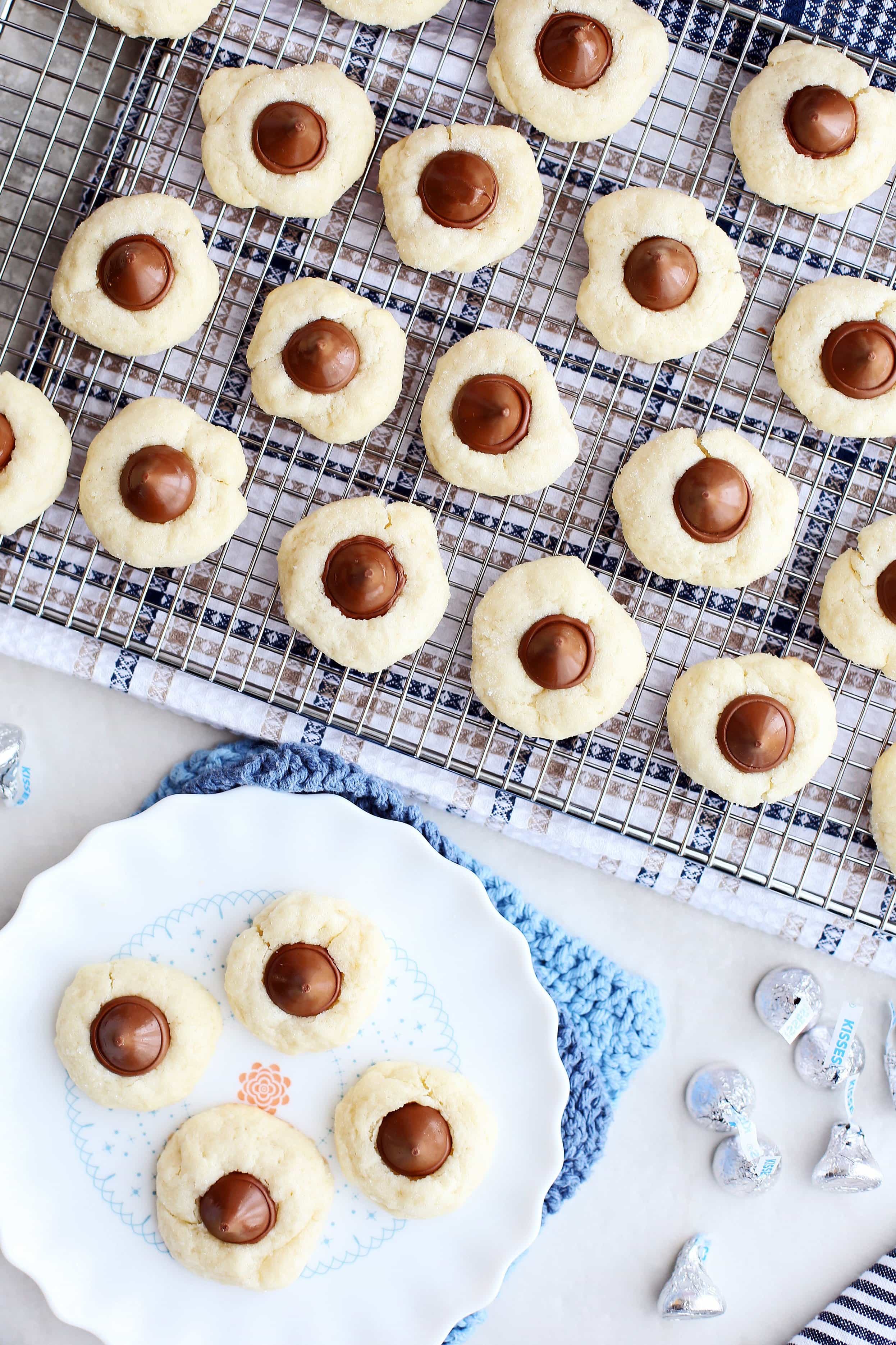 Overhead view of Cream Cheese Kiss Cookies on a metal cooling rack and on a white plate.