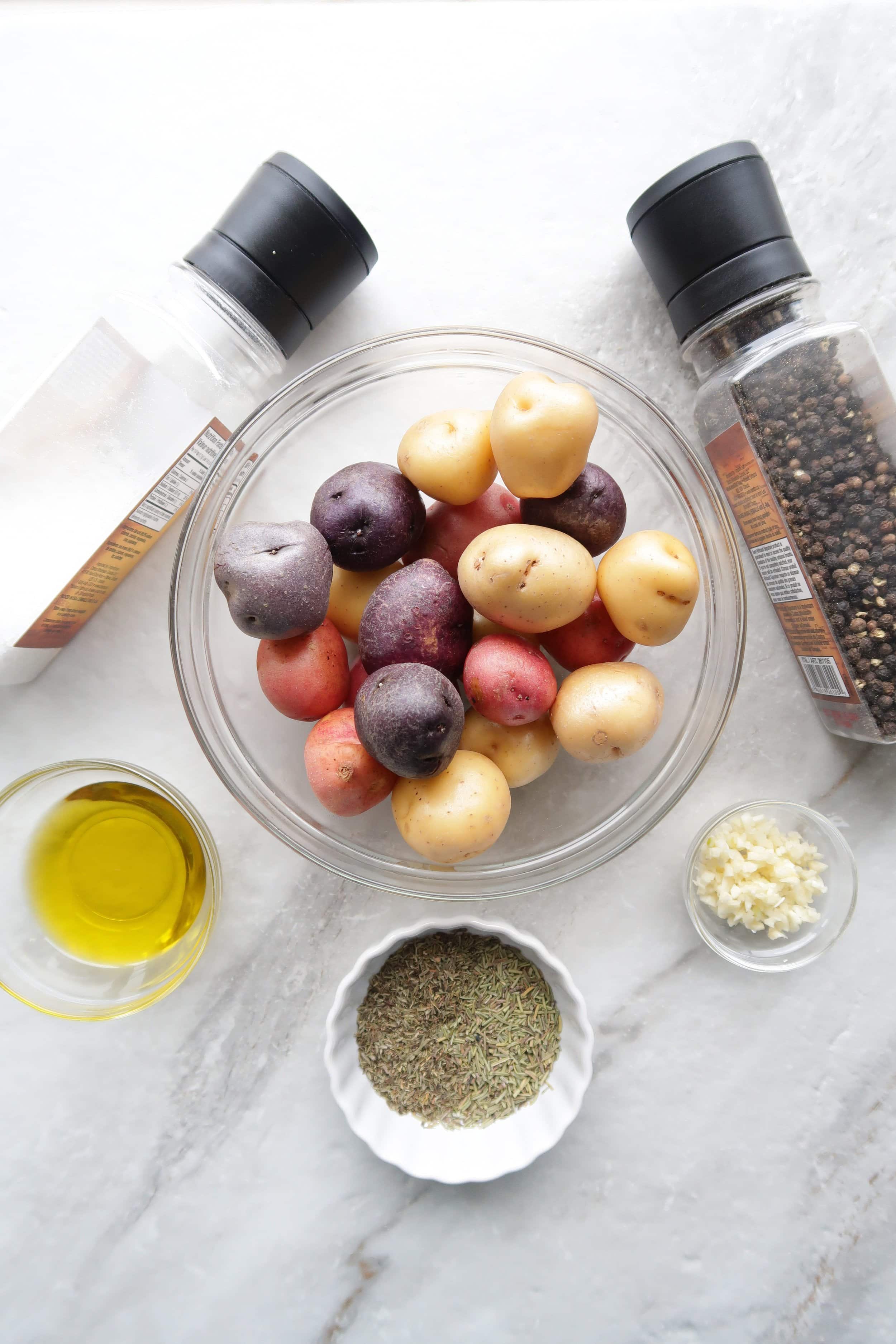 Bowls of colourful baby potatoes, olive oil, garlic, and herbs.