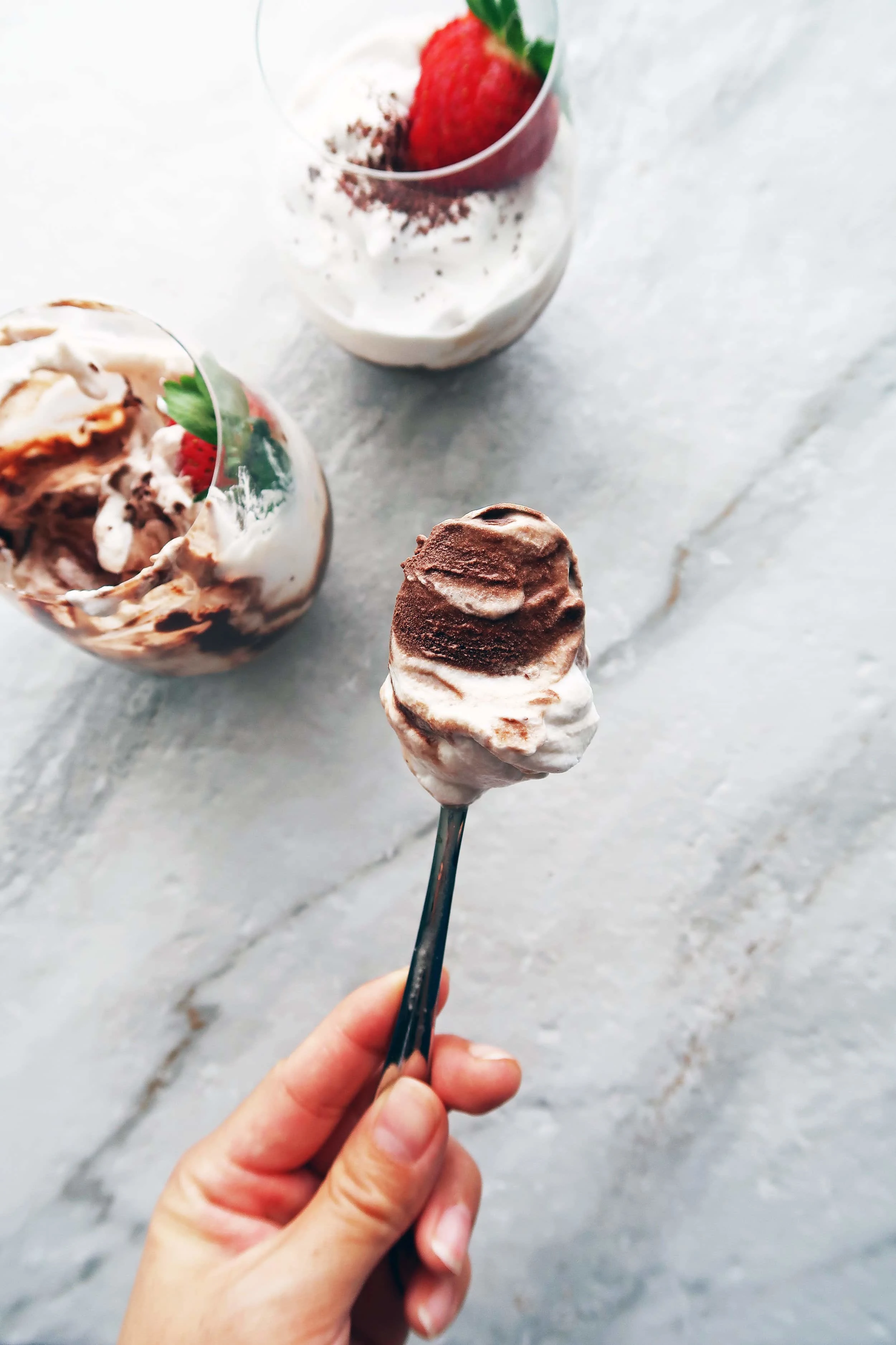 A spoon showing a swirl of dark chocolate mousse and coconut whipped cream.