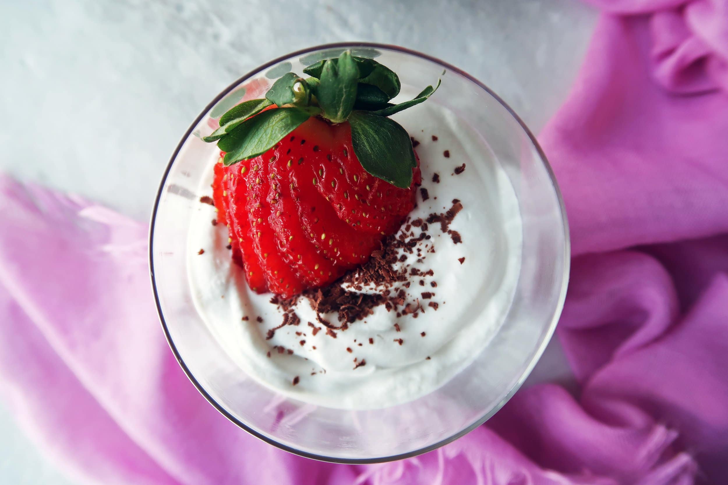 A sliced strawberry on top of coconut whipped cream.