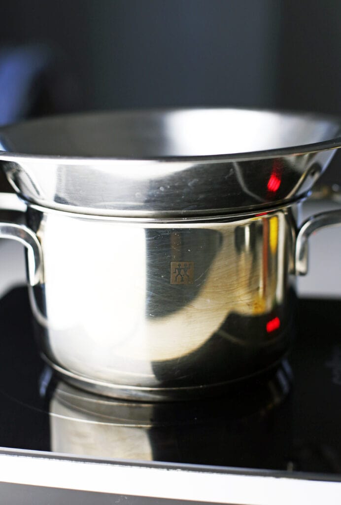 A saucepan with a stainless steel bowl nestled on top of the saucepan to create a double boiler.