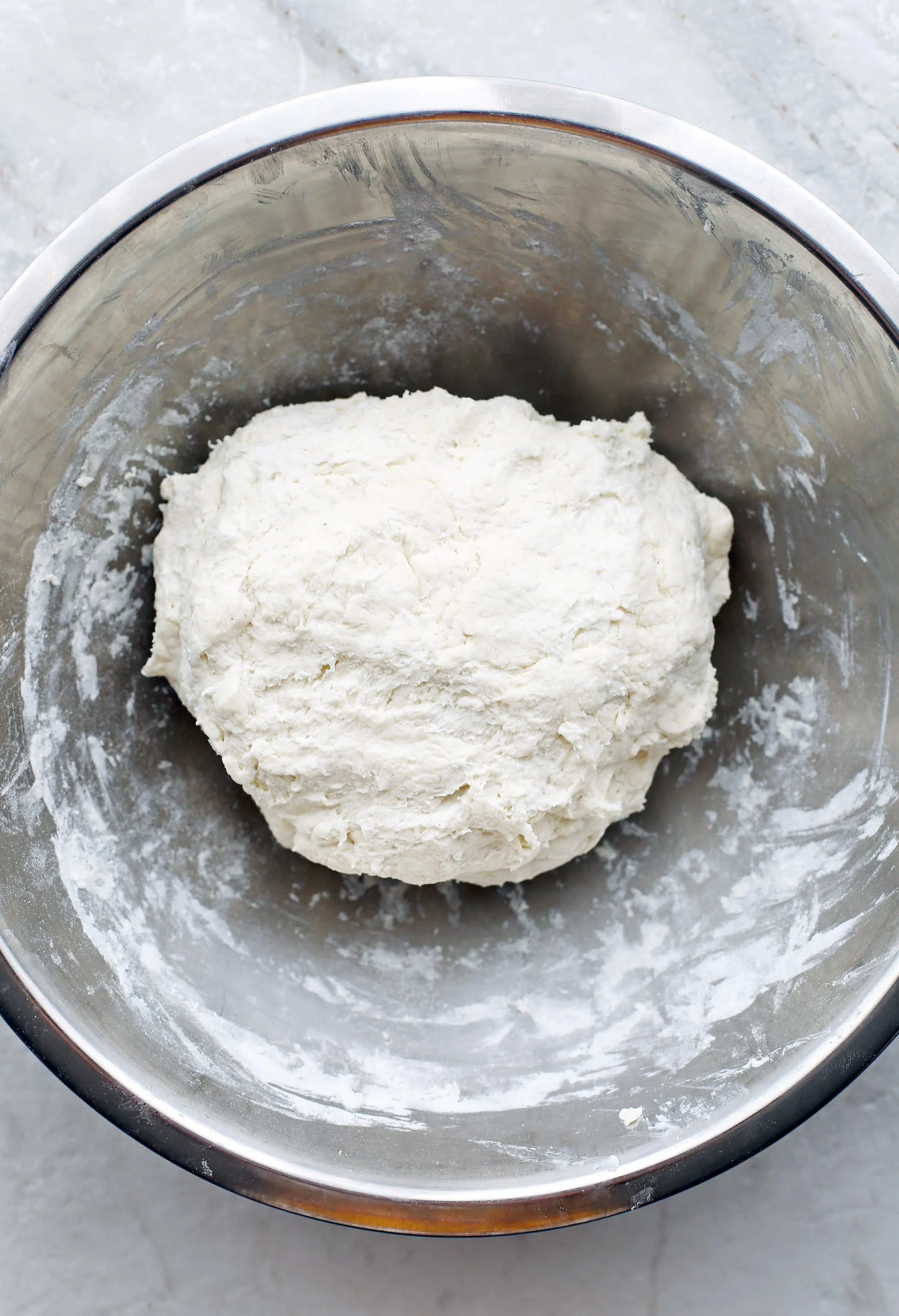 Greek yogurt, all-purpose flour, and baking powder combined together into a dough in a large metal bowl.