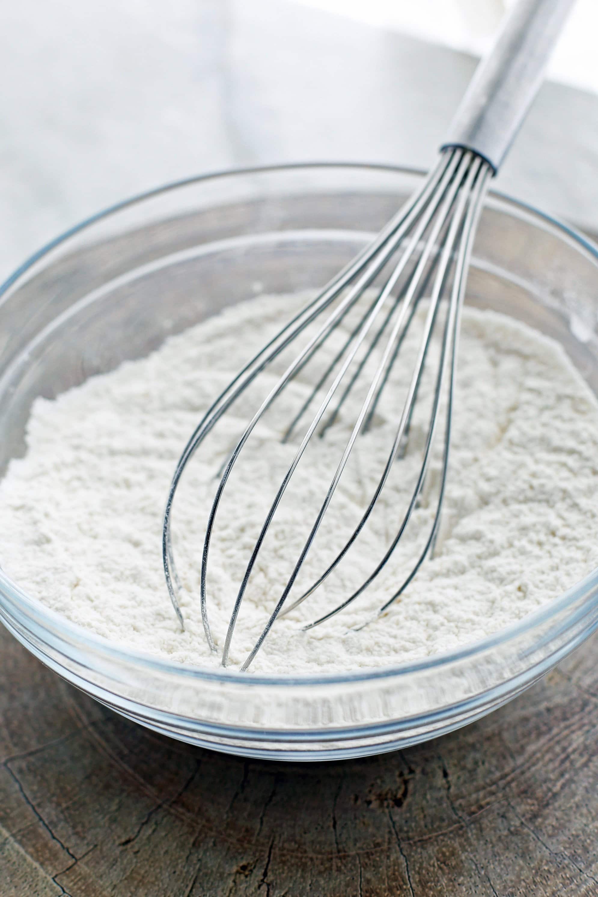 Dry baking ingredients in a glass bowl with a wire whisk.