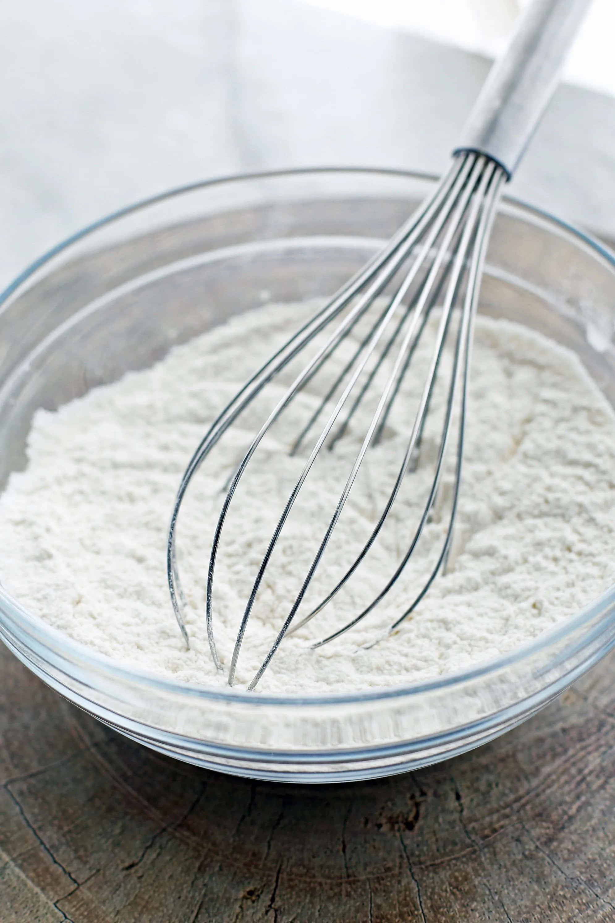 Dry baking ingredients in a glass bowl with a wire whisk.