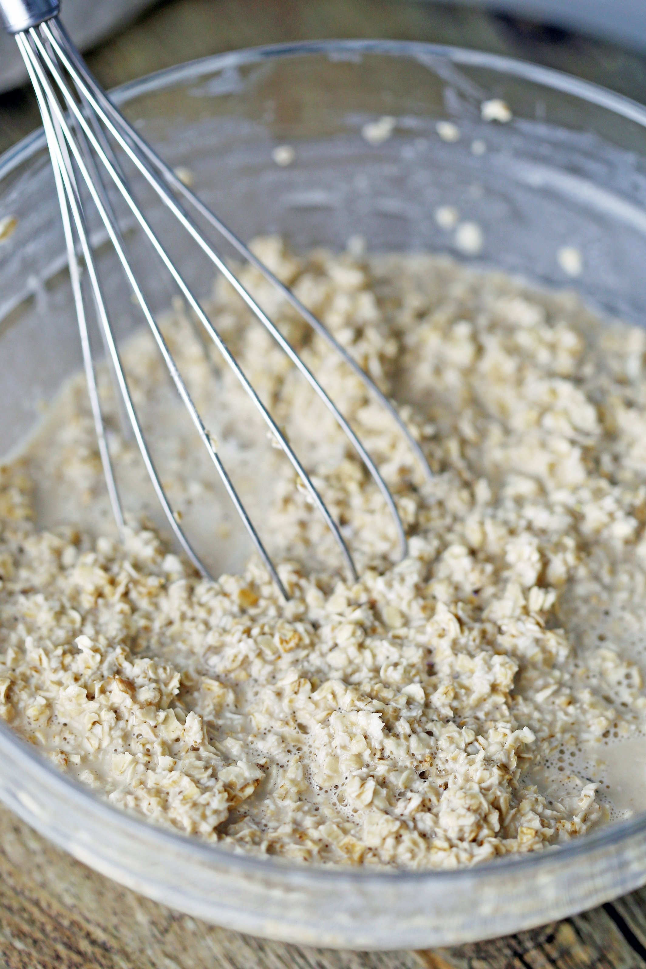 A glass bowl containing rolled oats, earl grey tea, almond milk, honey, and vanilla extract.