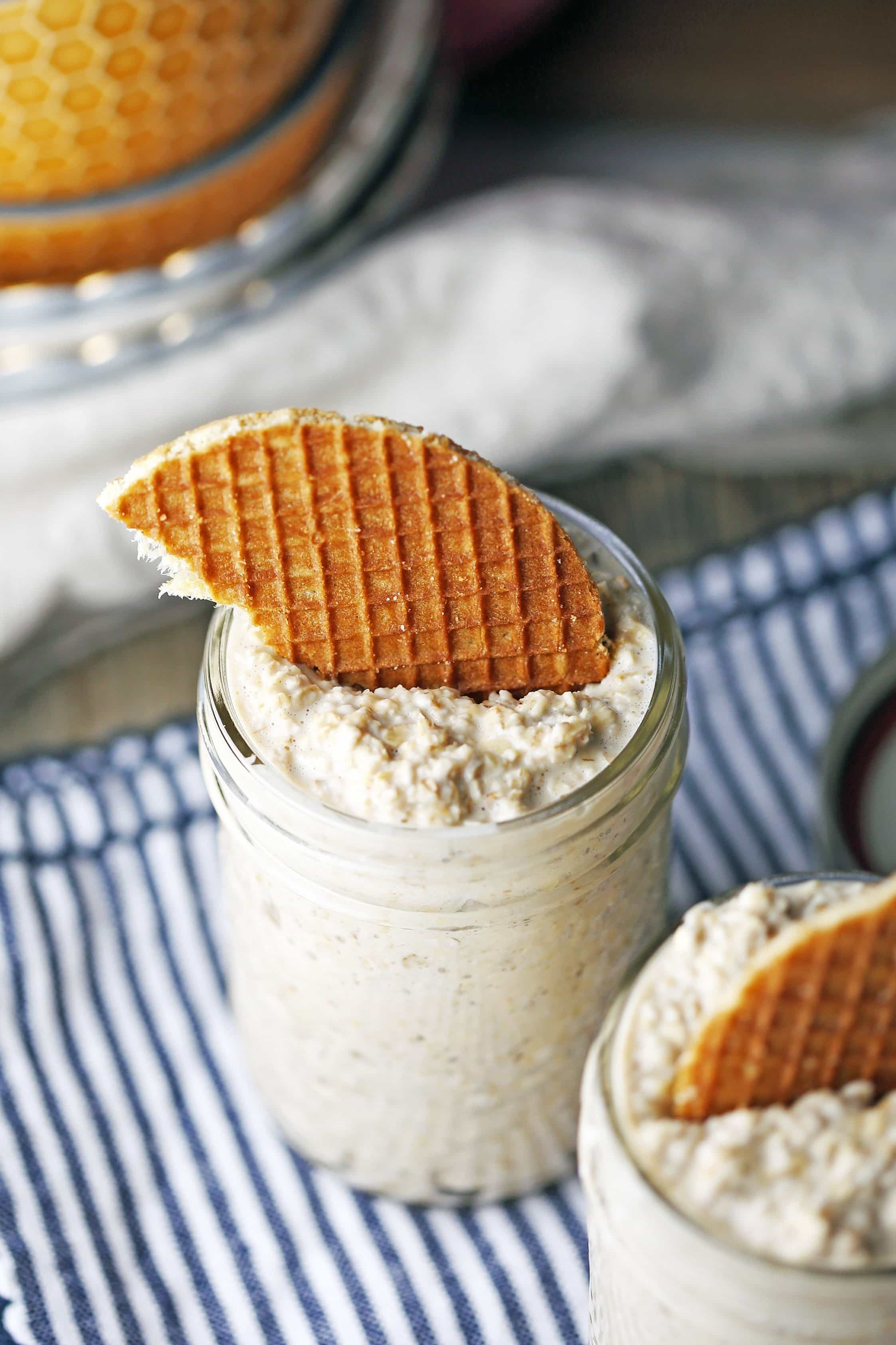 A close-up of a mason jar full of Vanilla Earl Grey Overnight Oats topped with half a stroopwafel.