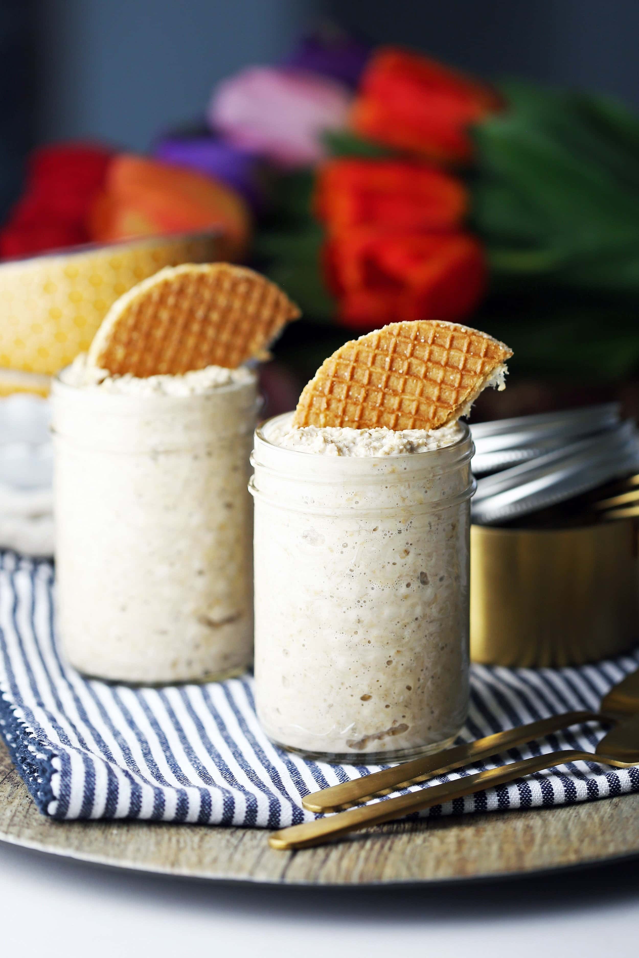 Two mason jars full of Vanilla Earl Grey Overnight Oats topped with half a stroopwafel.