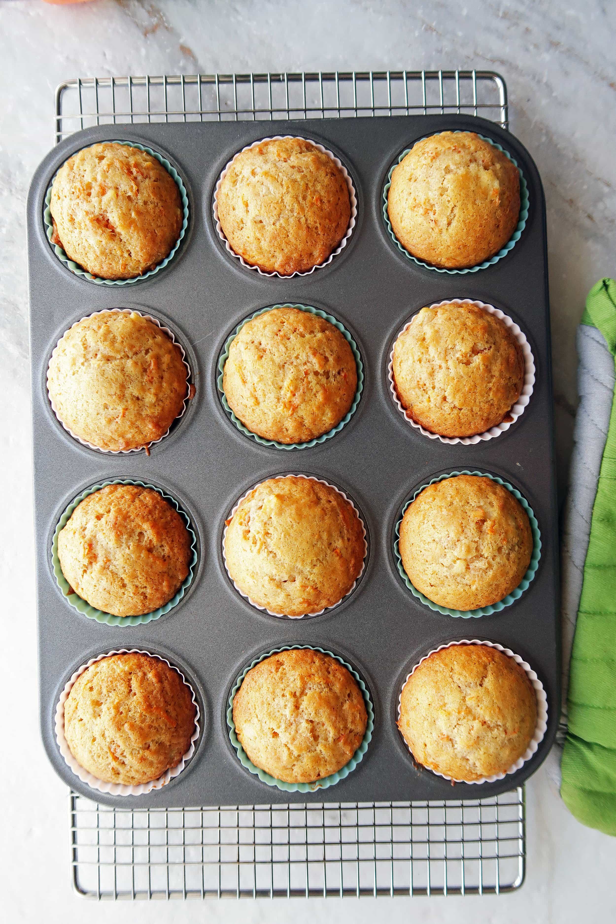 A dozen golden brown baked Easy Carrot Pineapple Muffins in a muffin tin.