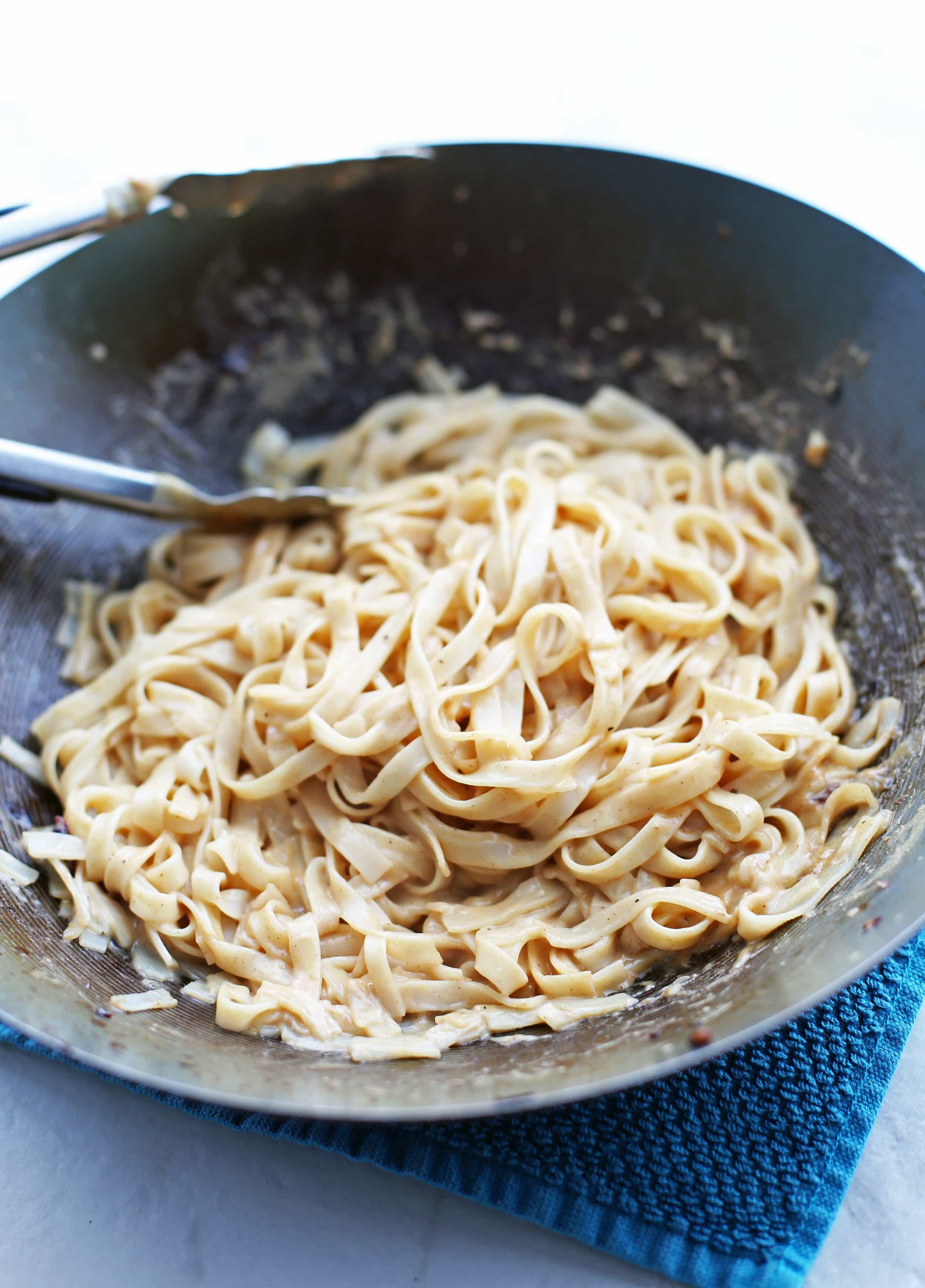 Rice stick noodles combined with peanut sauce in a large wok.