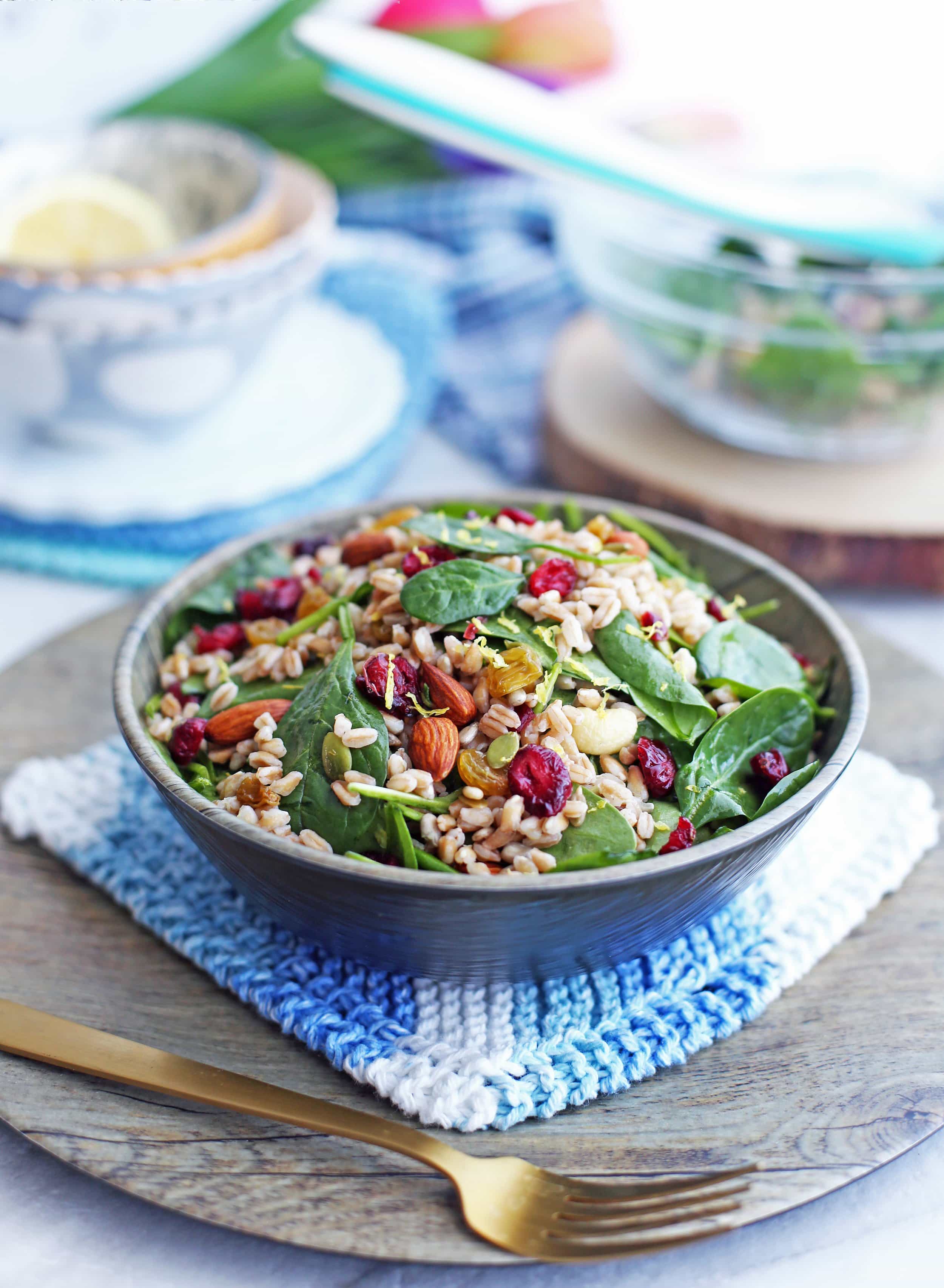 Farro and Spinach Salad with Dried Fruit and Nuts in a wooden bowl;fork in front of the bowl.