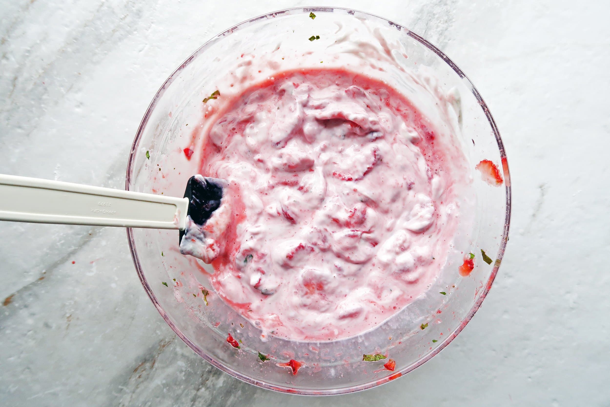 A bowl of creamy Greek yogurt combined with a refreshing strawberry and mint puree.