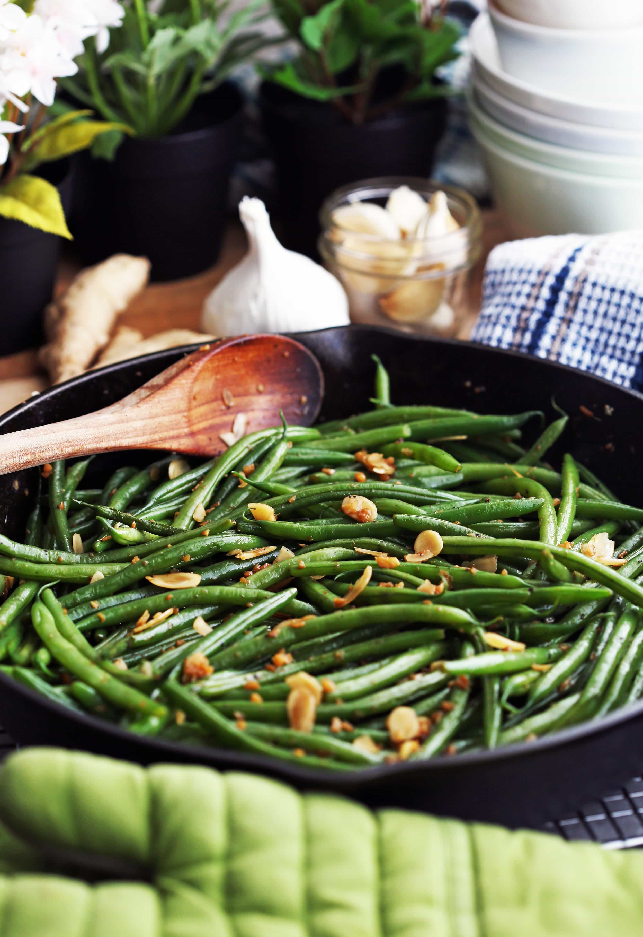 Sautéed green beans with ginger, garlic, and almonds in an large cast iron skillet.