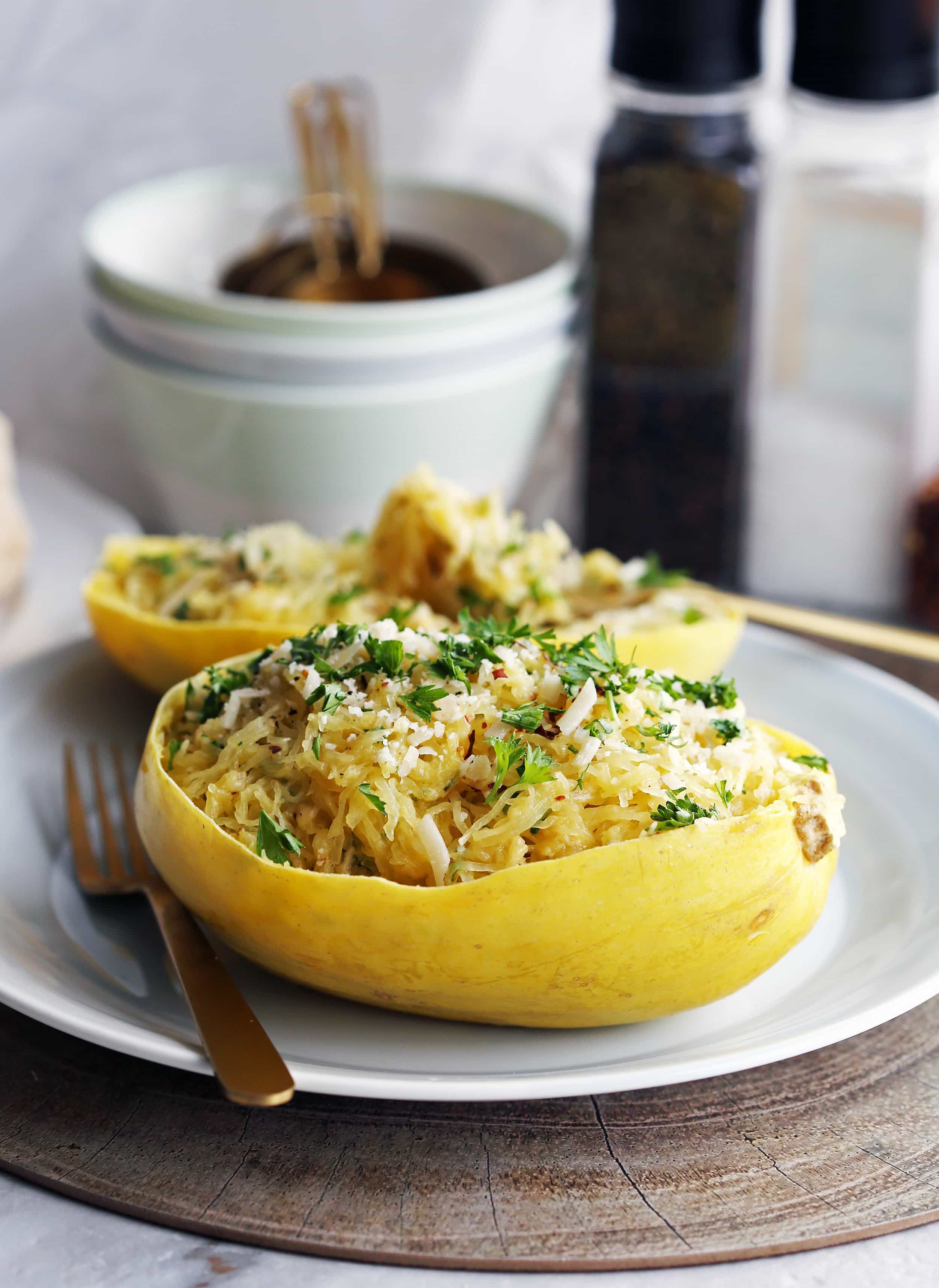 Instant Pot Garlic Parmesan Spaghetti Squash placed in a halved hollowed spaghetti squash shell (skin) with a fork on the side.