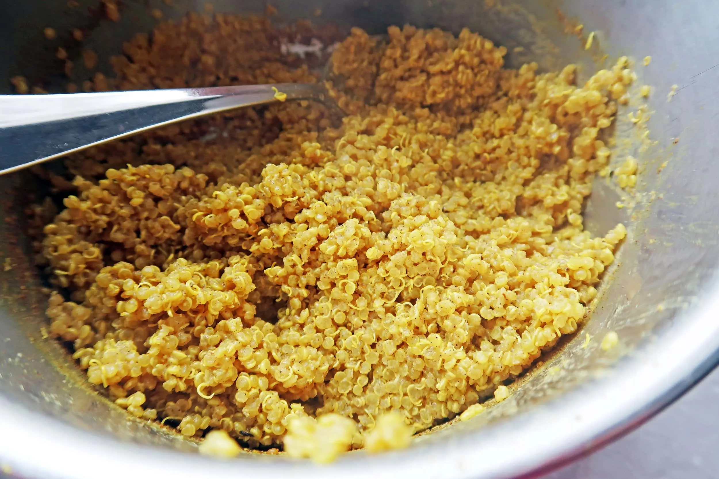 Cooked quinoa that has been cooked in golden (turmeric) milk in a small pot.