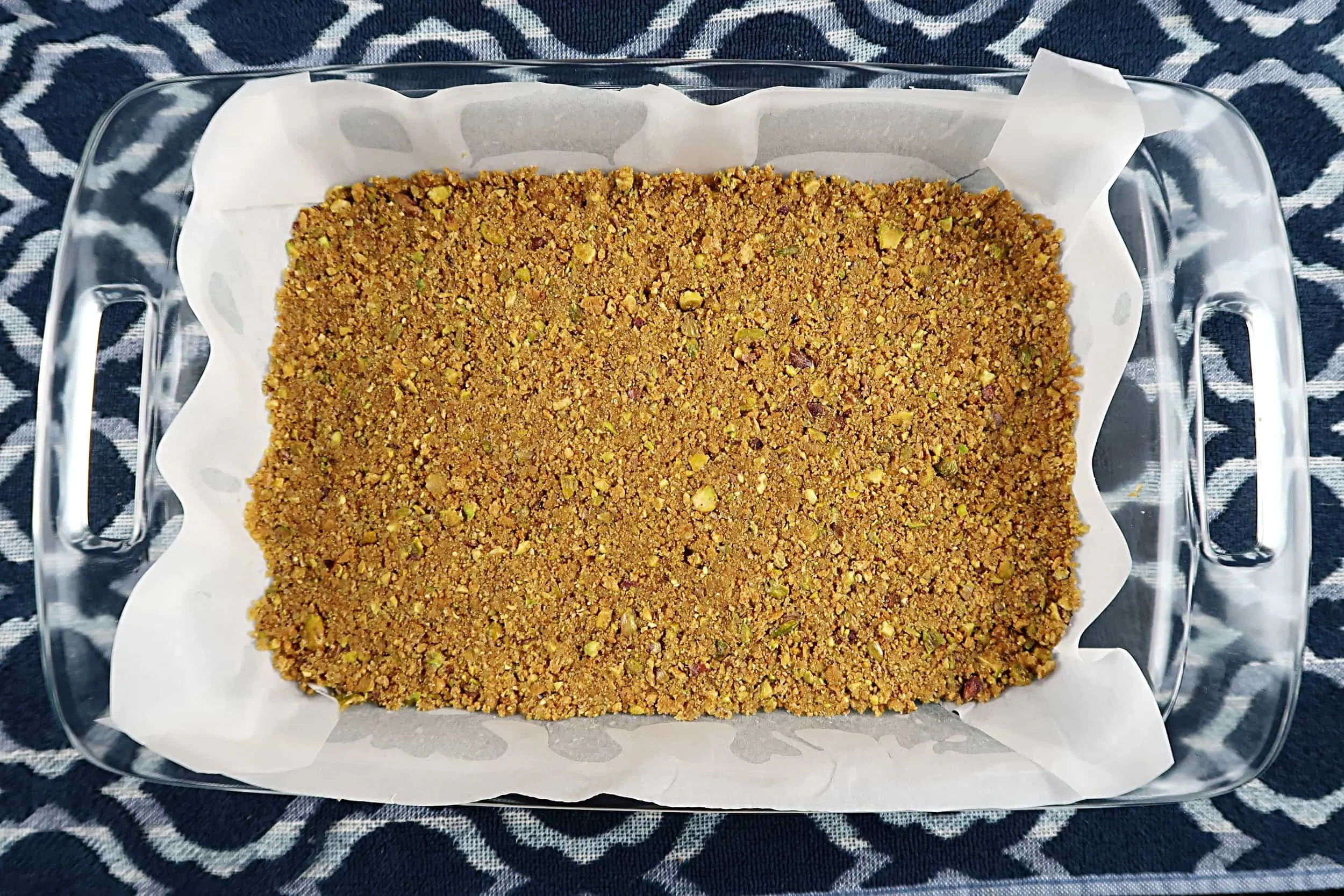Pistachio and graham cracker crust pressed into a baking dish.