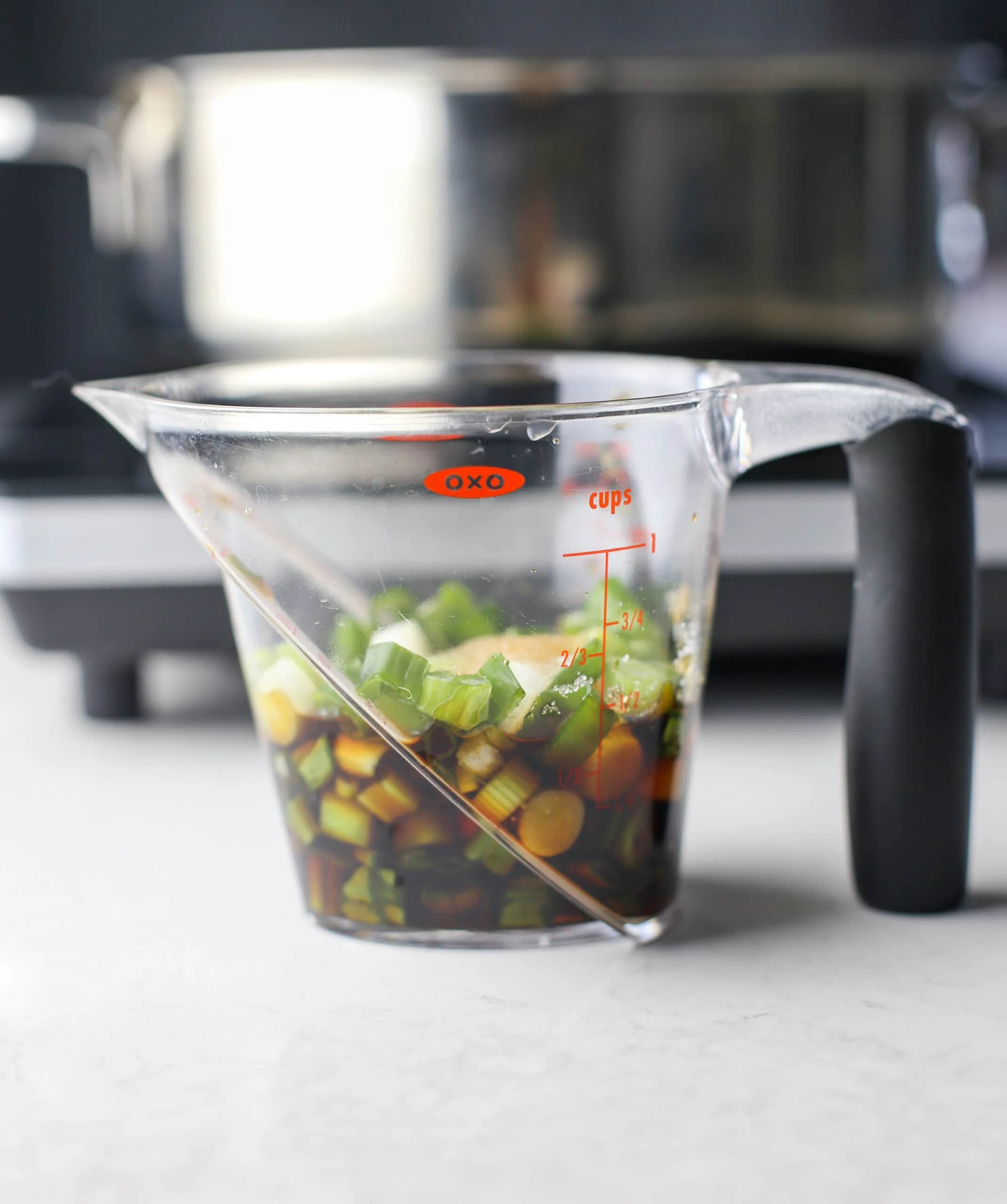 Chopped green onions, soy sauce, rice vinegar, sesame oil, and sugar in a measuring cup.