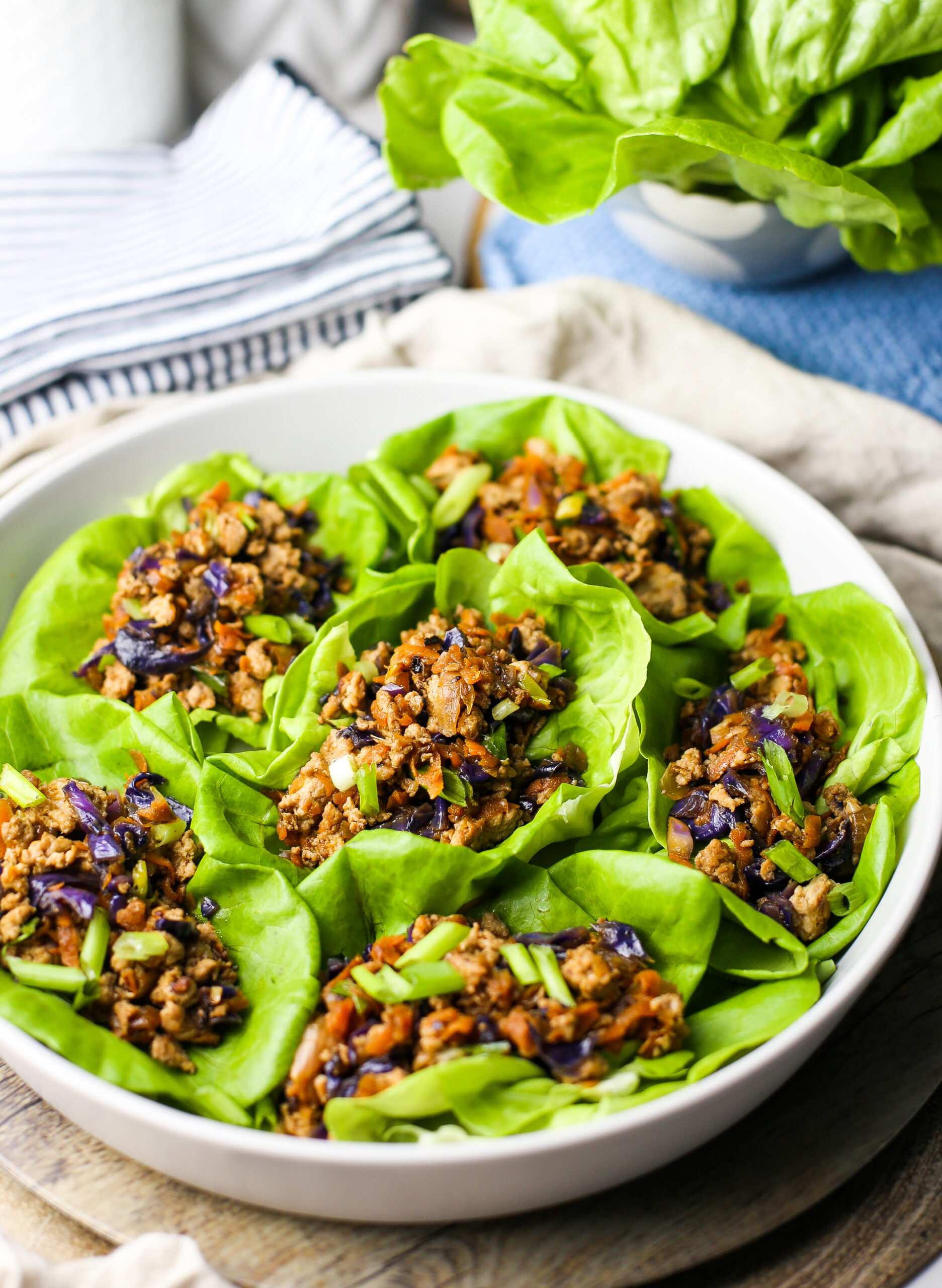 Side view of ground chicken lettuce wraps in a round grey platter.