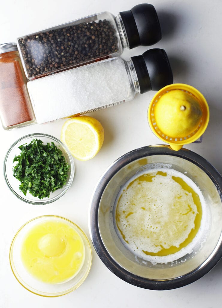 Bowls of egg yolks, melted butter, parsley, and lemon juice with ground paprika, black pepper, and sea salt in shakers.