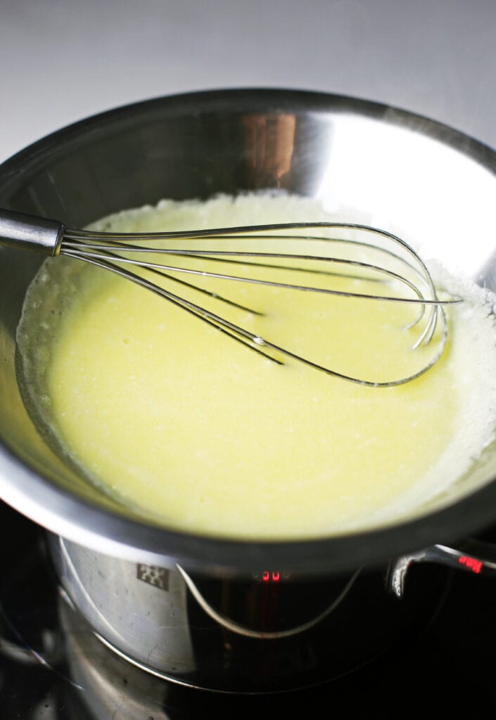Homemade hollandaise sauce in a diy double boiler (a saucepan with a stainless steel bowl on top).
