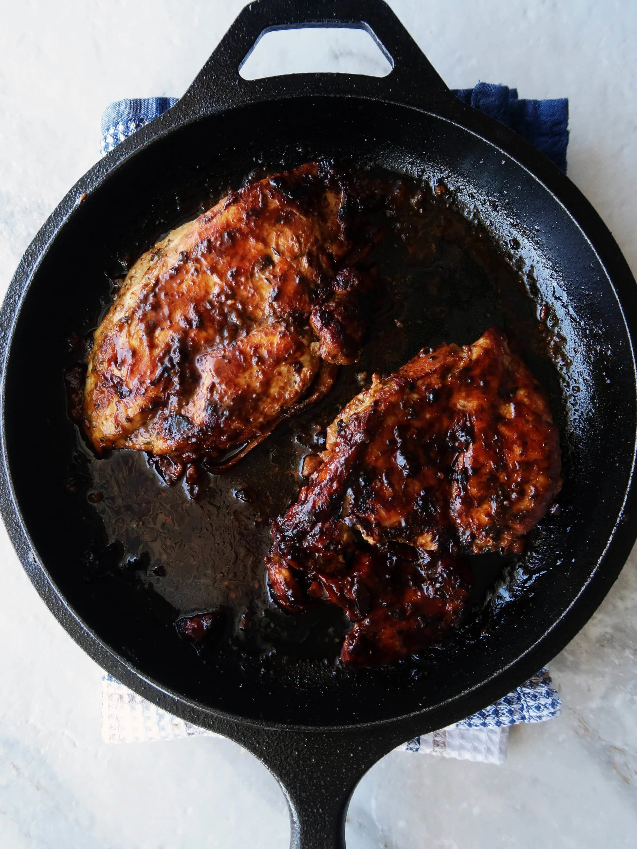 Two large cooked honey mustard chicken breasts in a cast iron skillet.