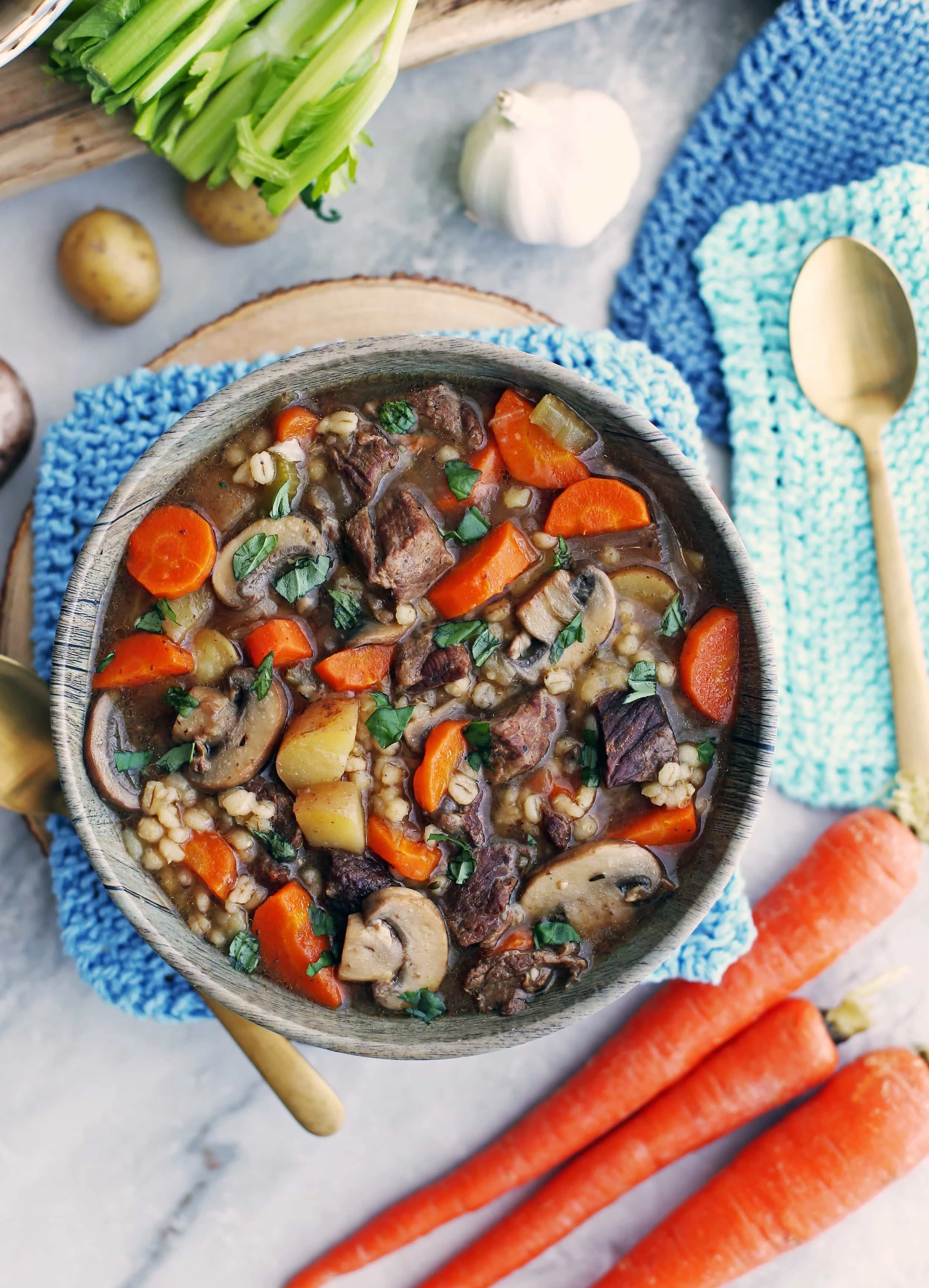 Beef barley mushroom soup with fresh vegetables (e.g. carrots, celery, potatoes, onion) in a bowl.