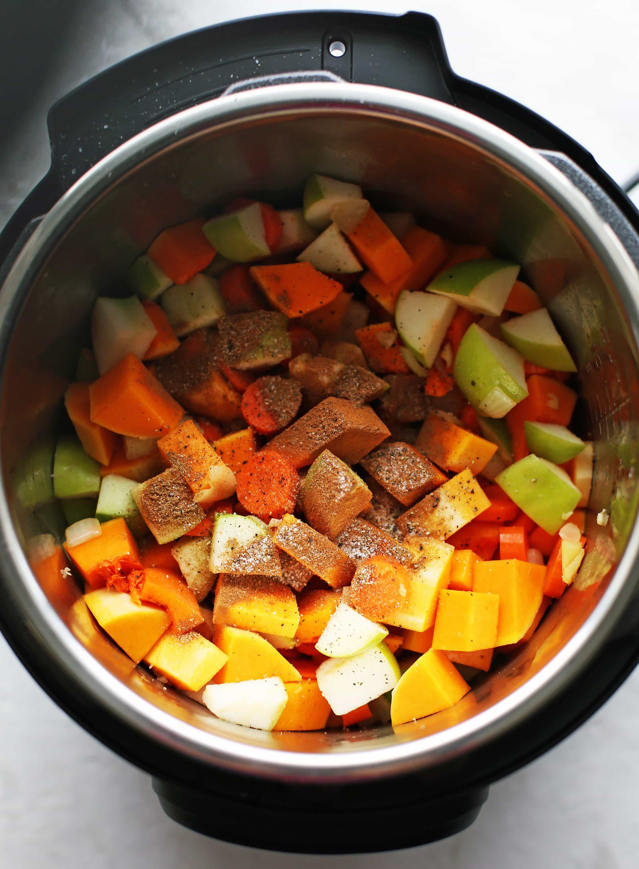 Sautéed onions, ginger, and garlic with chopped butternut squash, granny smith apples, carrots, and spices in the Instant Pot.