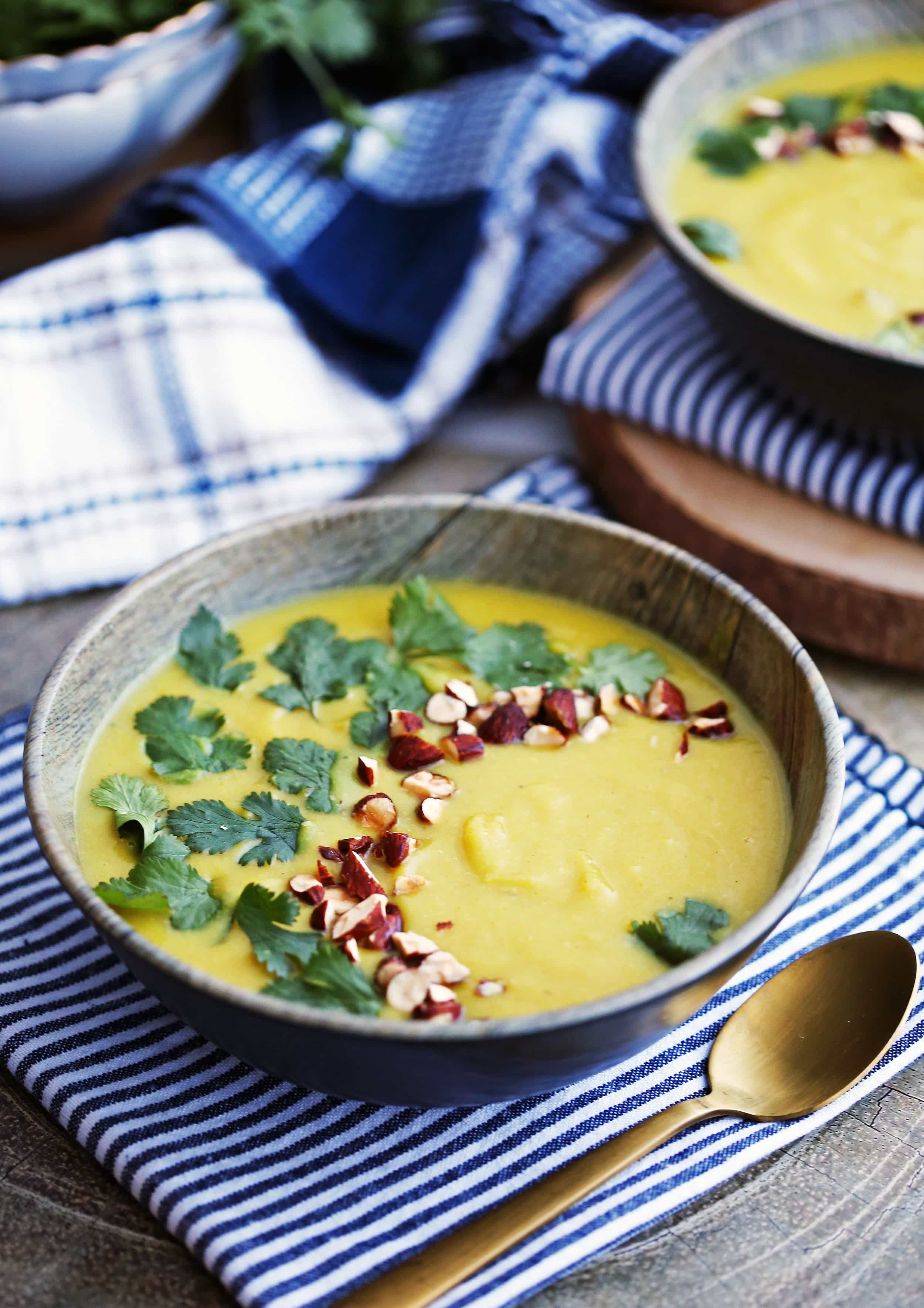 A bowl of Instant Pot Turmeric Cauliflower Potato Soup topped with fresh parsley and chopped almonds.