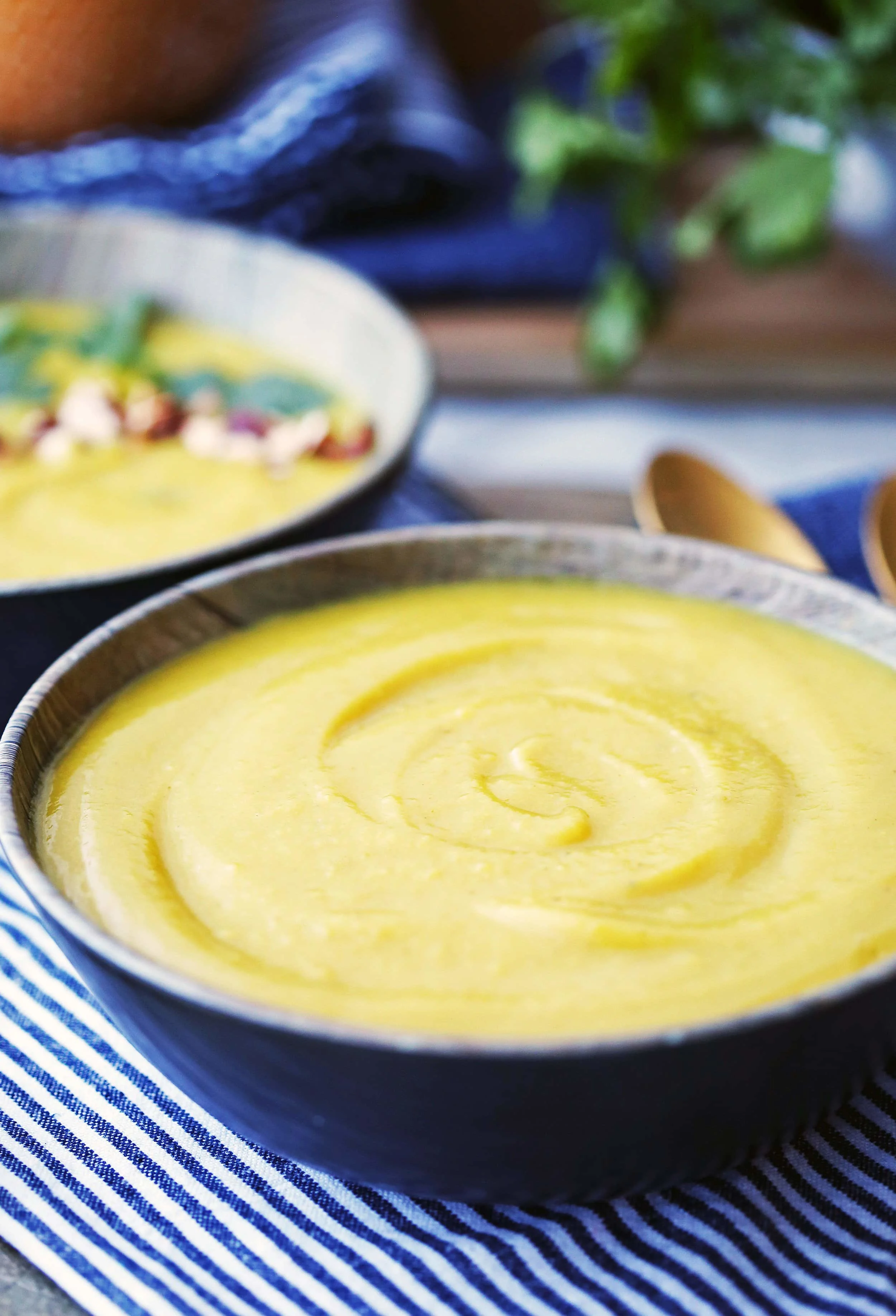 A creamy bowl of Instant Pot Turmeric Cauliflower Potato Soup on a blue and white striped towel.