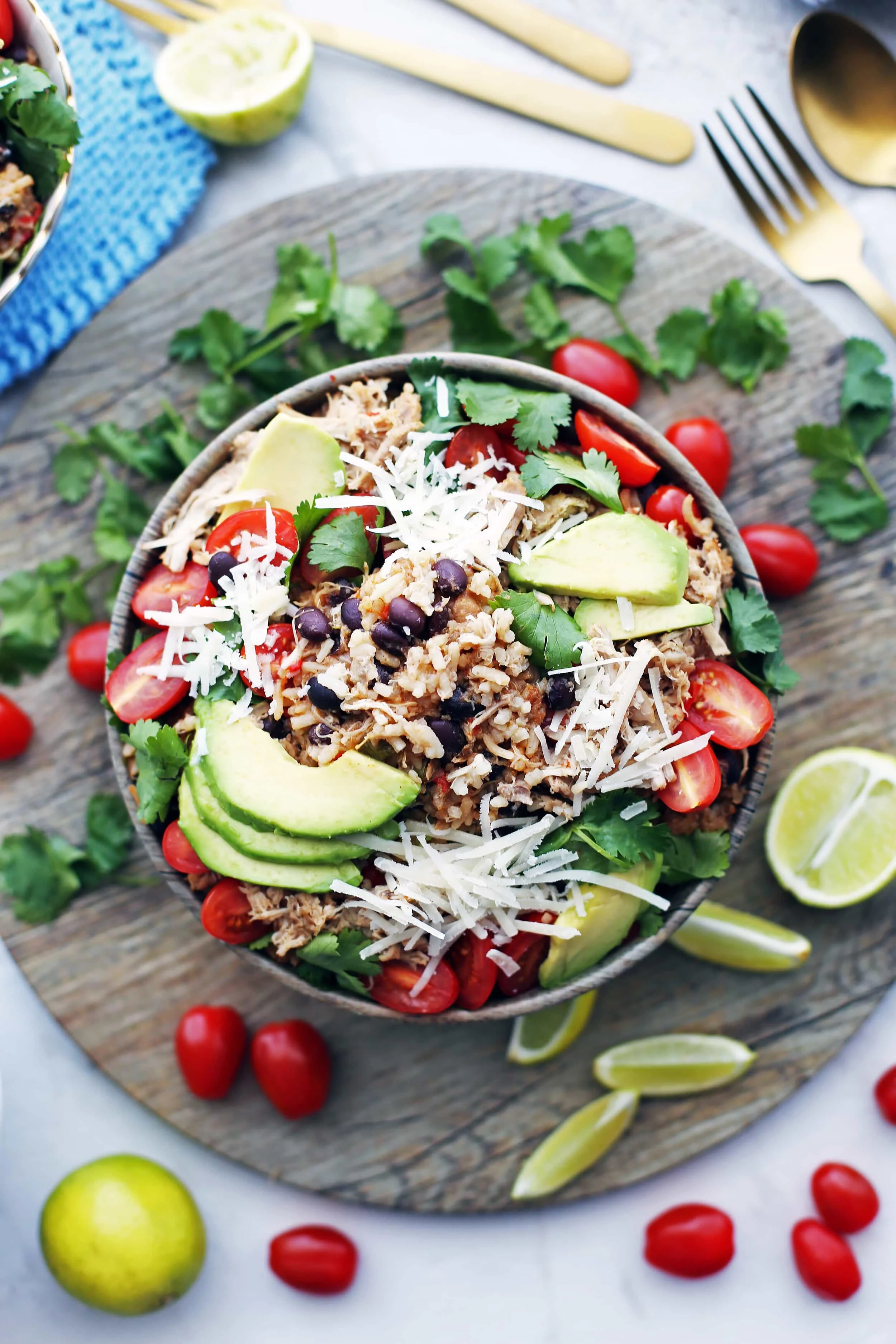 Overhead view of a bowl of instant pot chicken, black bean, and rice topped with avocado, tomatoes, cheese, and cilantro.