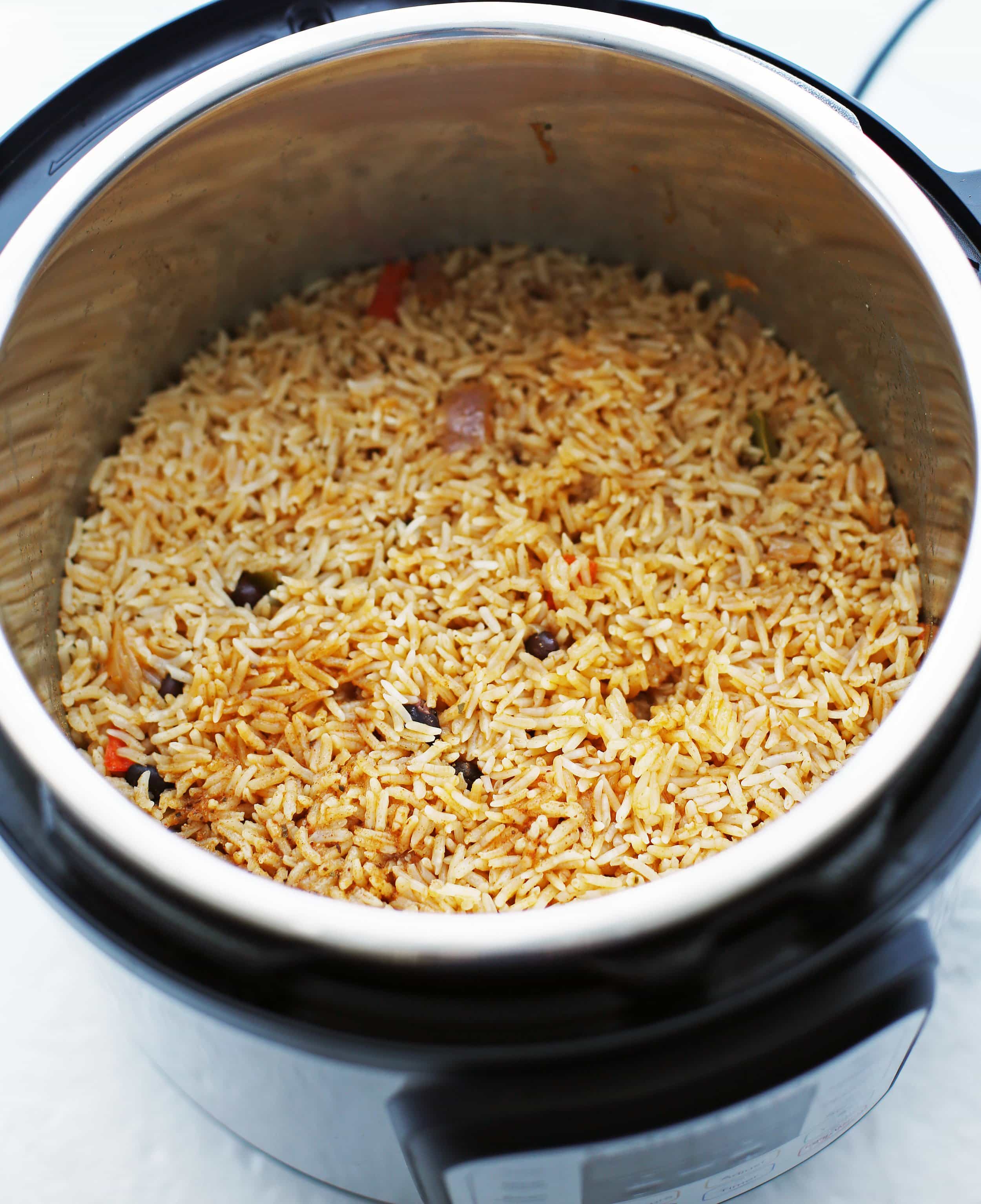 Cooked spiced rice on top of sauteed vegetables, black beans, and chicken thighs in the Instant Pot.