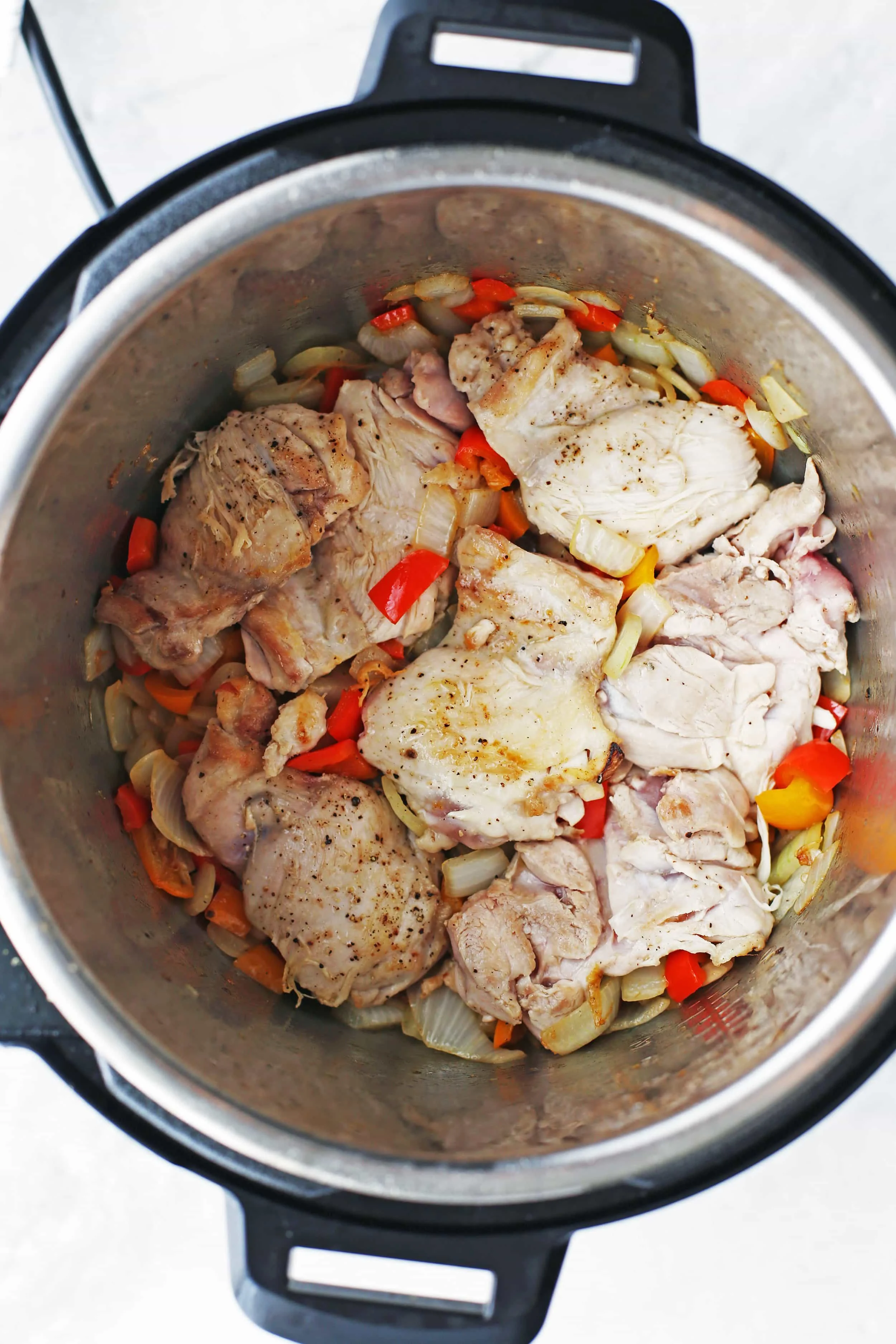 Browned chicken thighs and sautéed chopped bell pepper and onions in an Instant Pot.