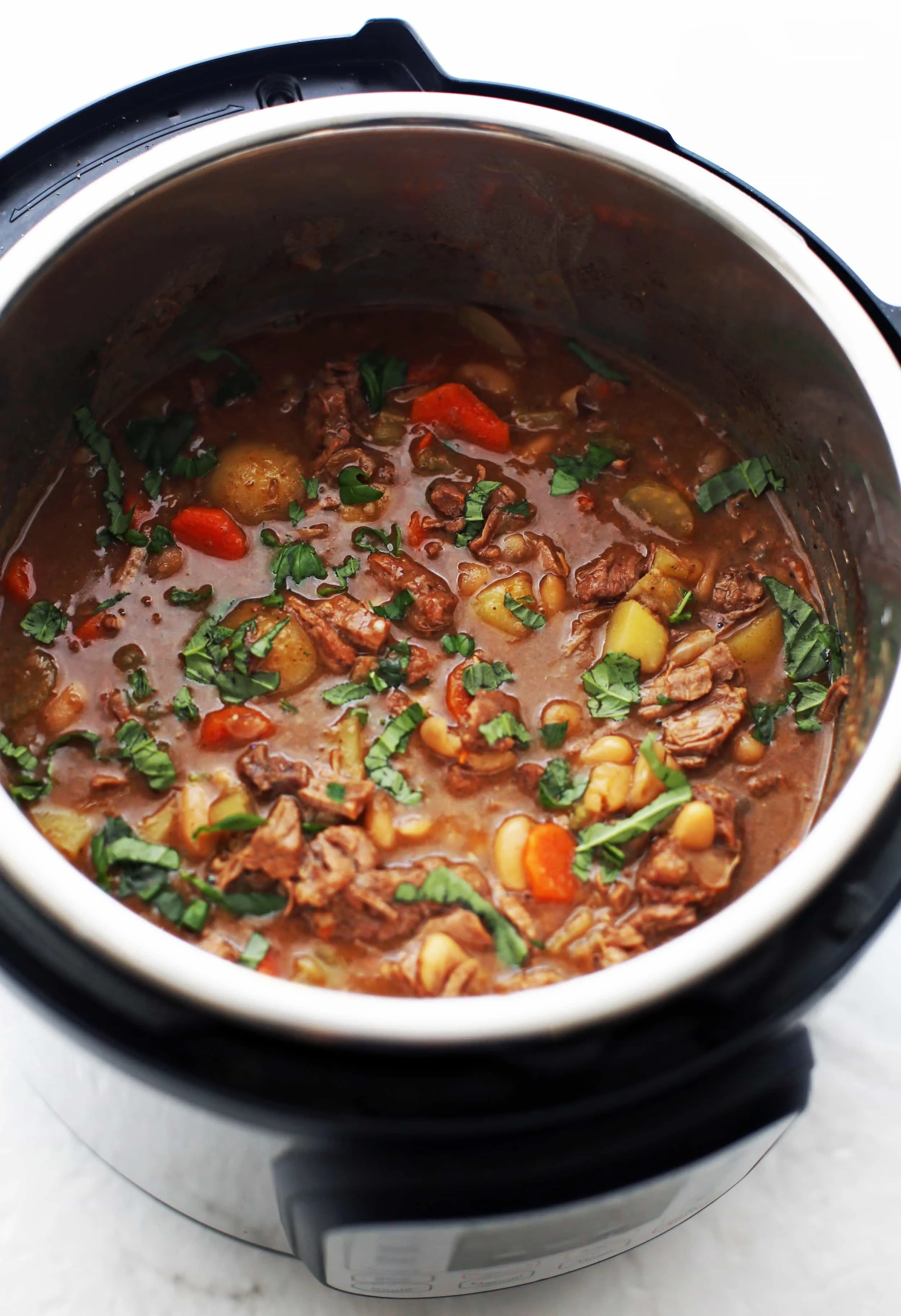 A top view of Chinese Five Spice Beef and Vegetable Stew with green basil on top in the Instant Pot.