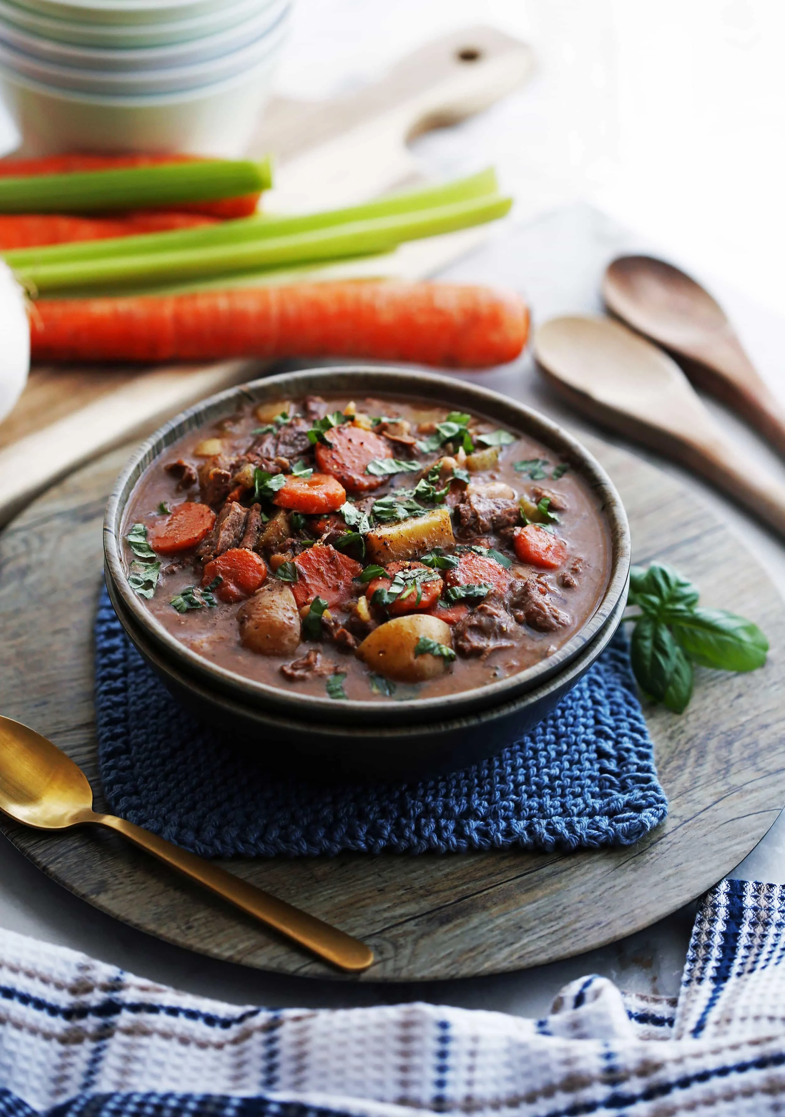 An side view of a bowl of Chinese Five Spice Beef and Vegetable Stew with fresh basil on top.