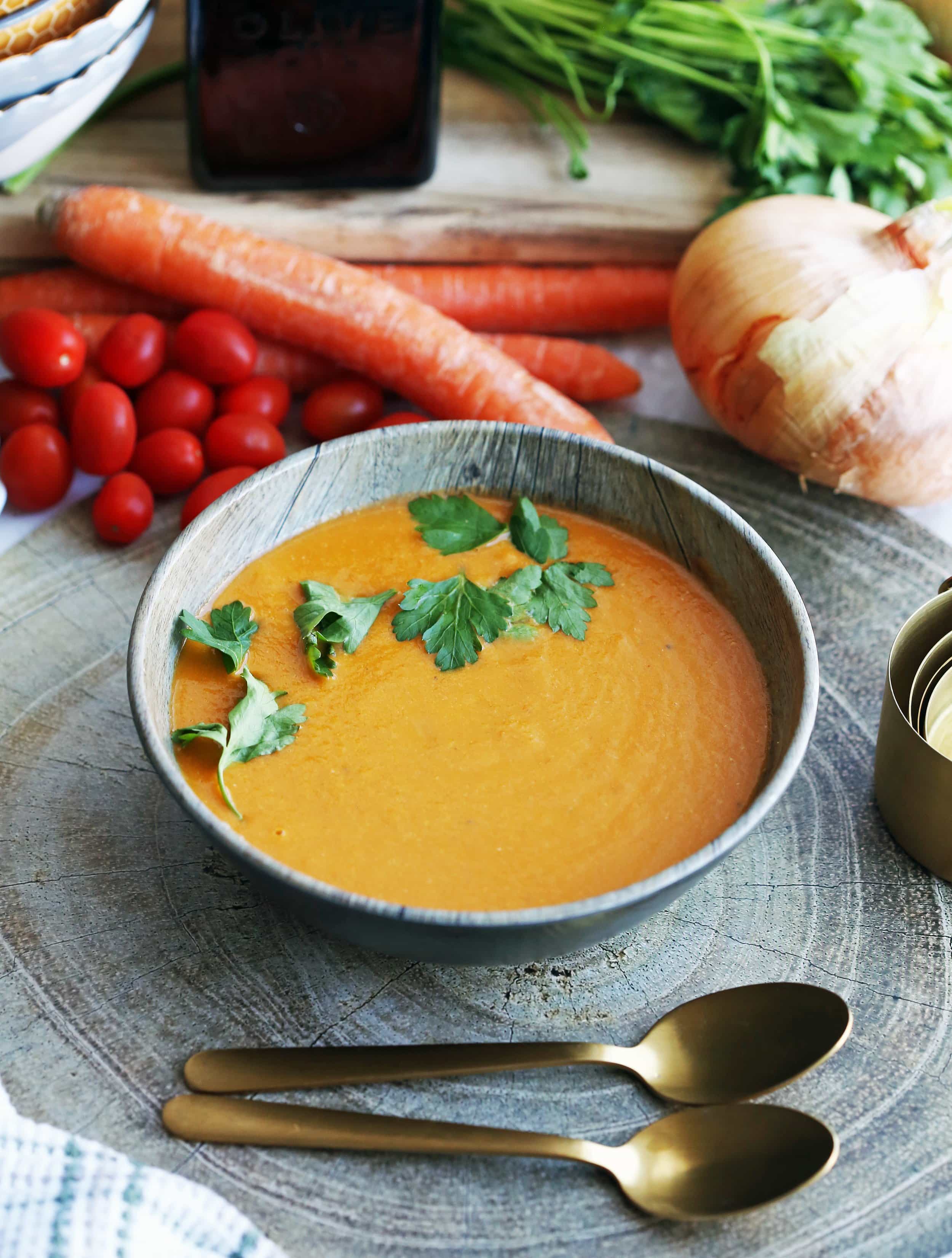 A wooden bowl full of Instant Pot homemade tomato soup with two spoons on the side.