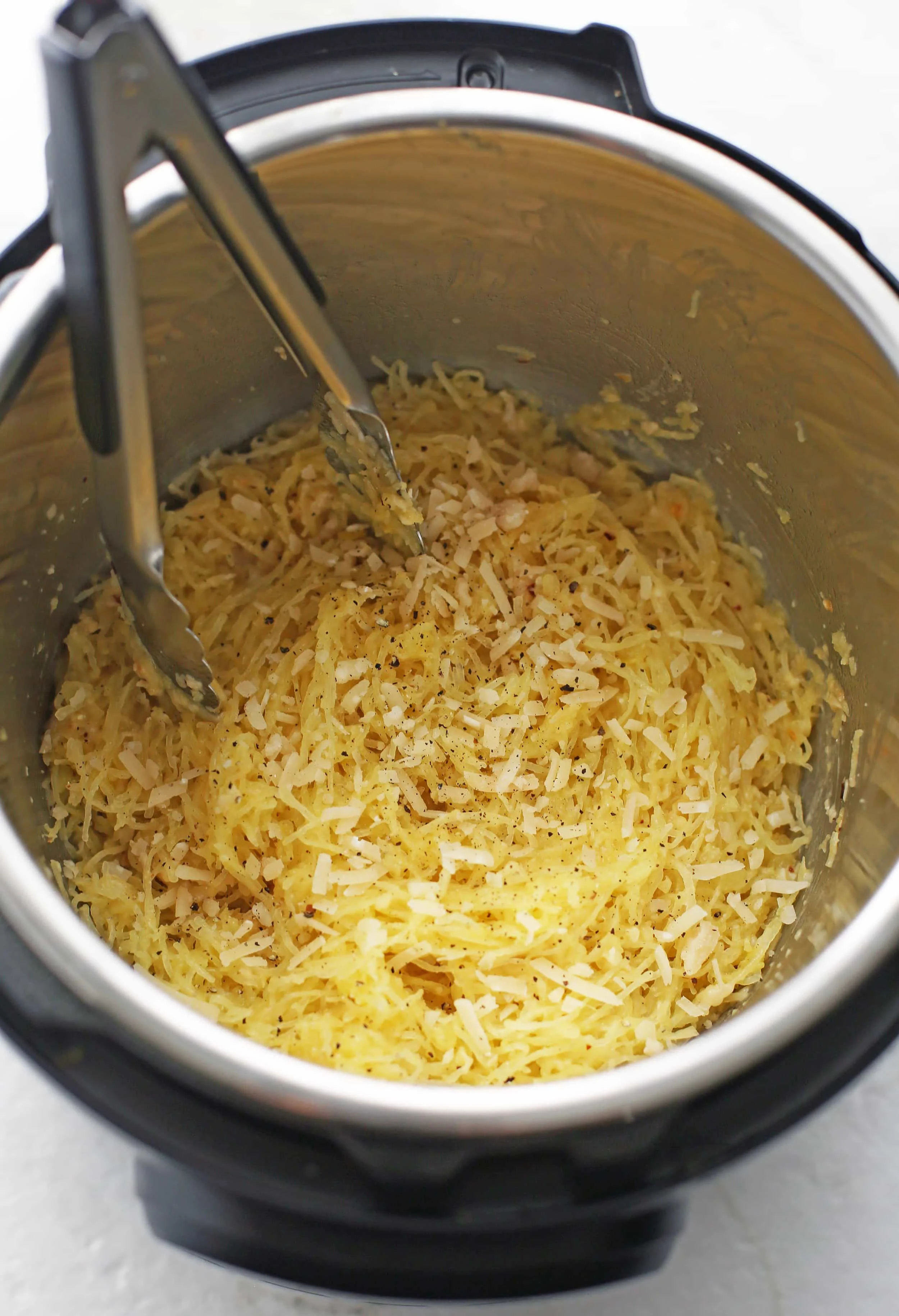 Cooked spaghetti squash mixed with olive oil, butter, spices, and garlic in the Instant Pot.