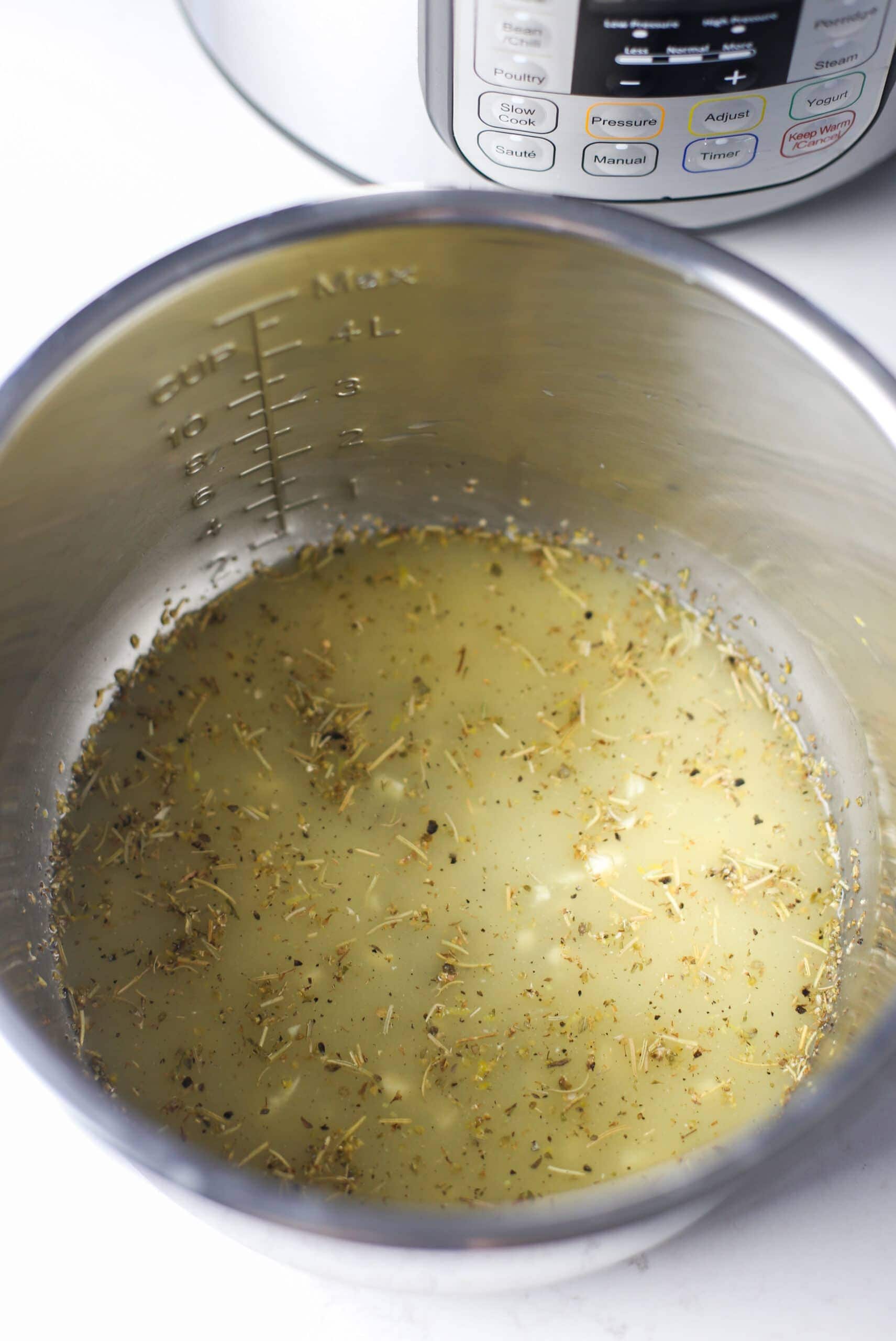 Chicken broth, lemon juice and zest, garlic, and dried herbs mixed together in the Instant Pot.